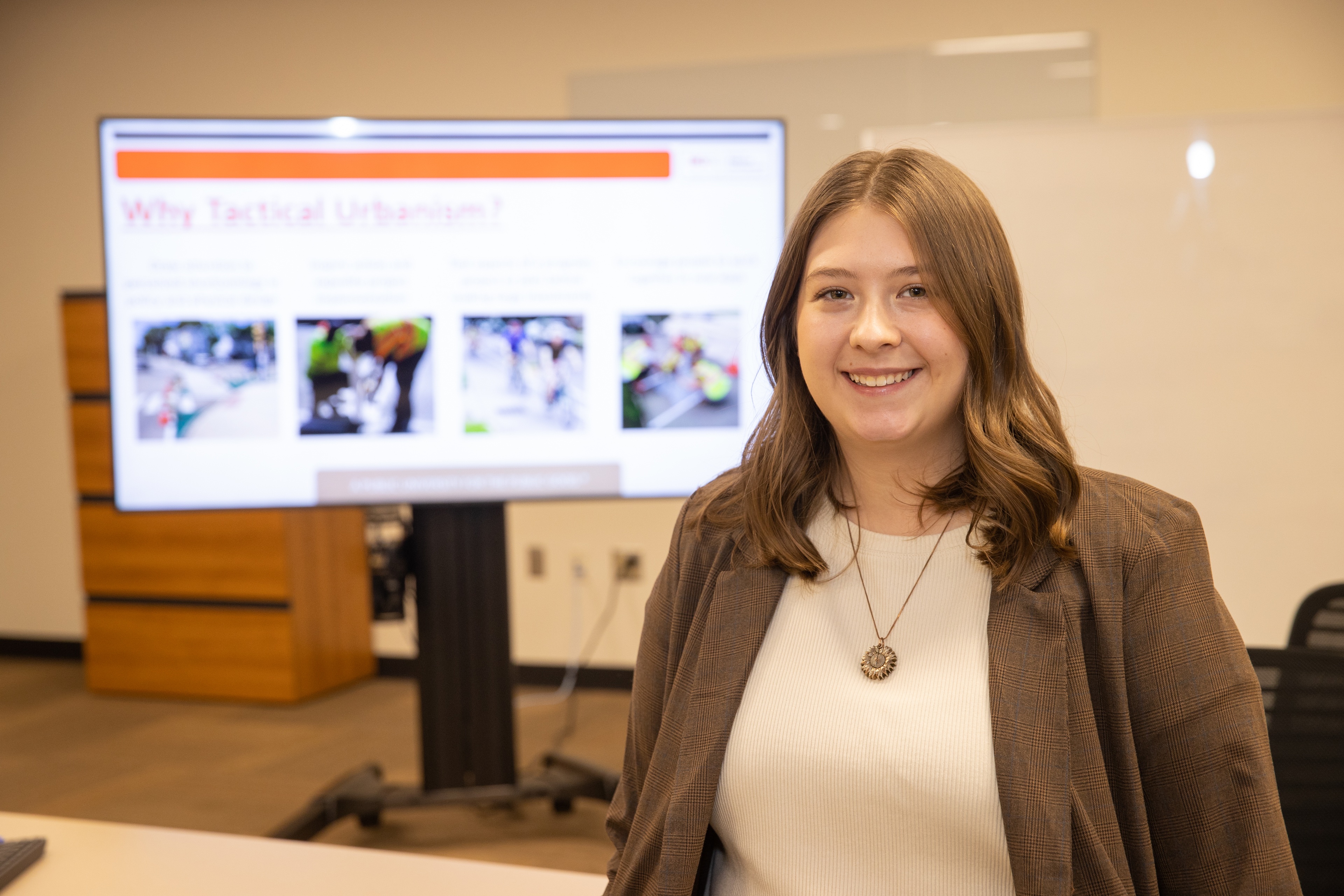 BGSU student poses in front of a large presentation screen