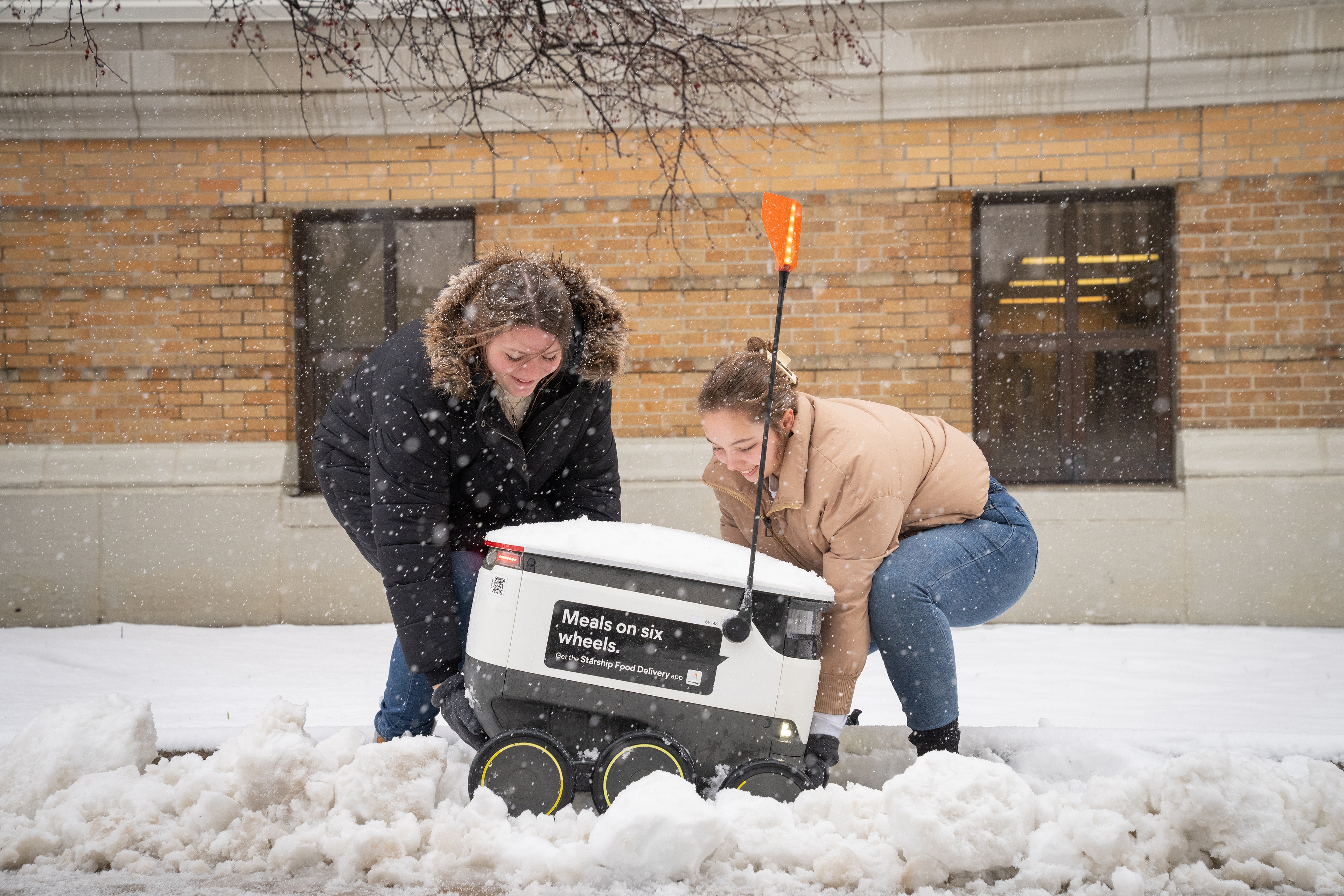 Students help a Starship robot out of the snow
