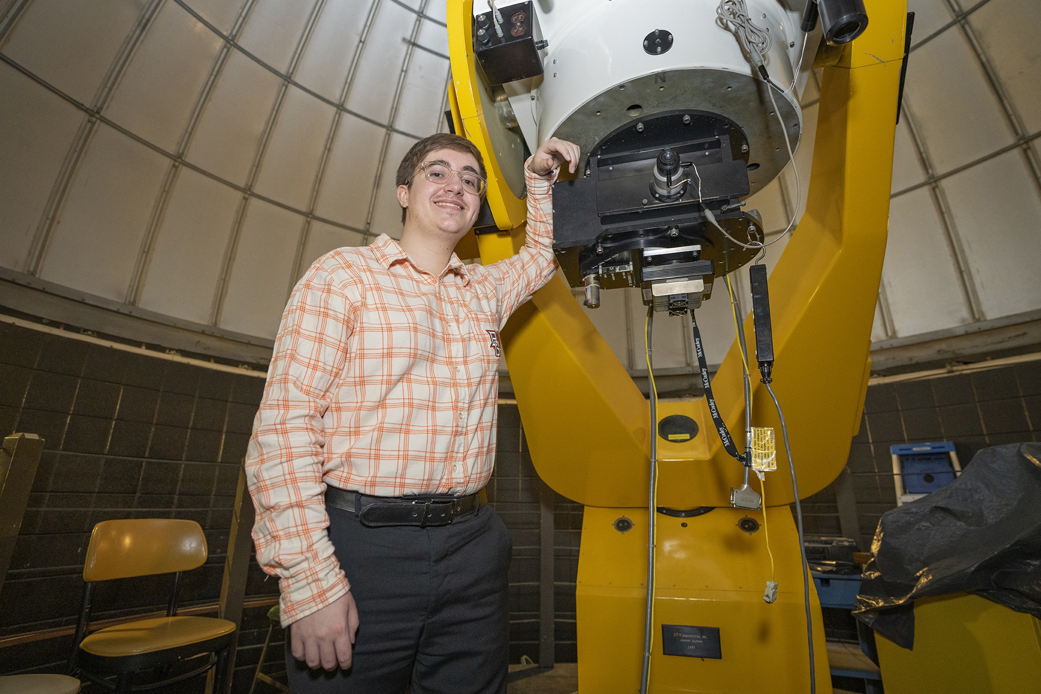 Devin Darr stands next to telescope on the roof of Overman Hall.