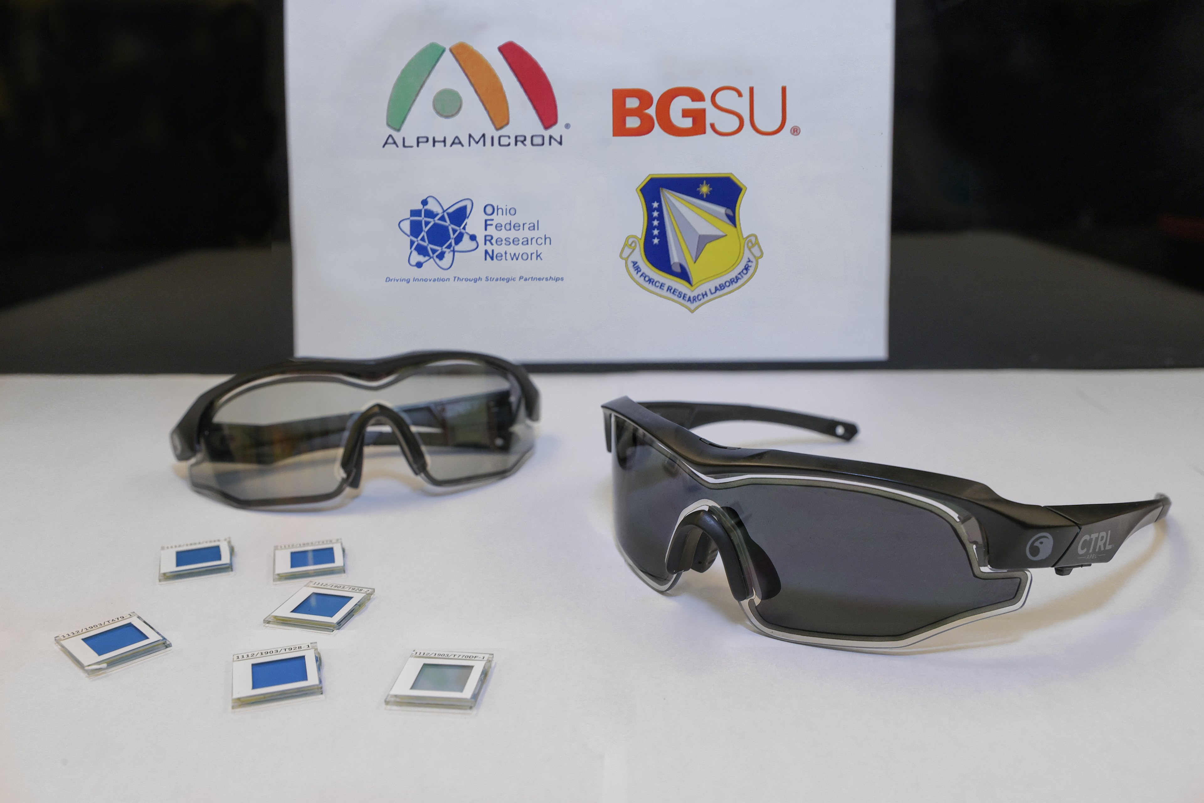 two pair of eyewear sitting on a paper with logos of BGSU, AlphaMicron, Ohio Federal Research Network, Air Force Research Laboratory 