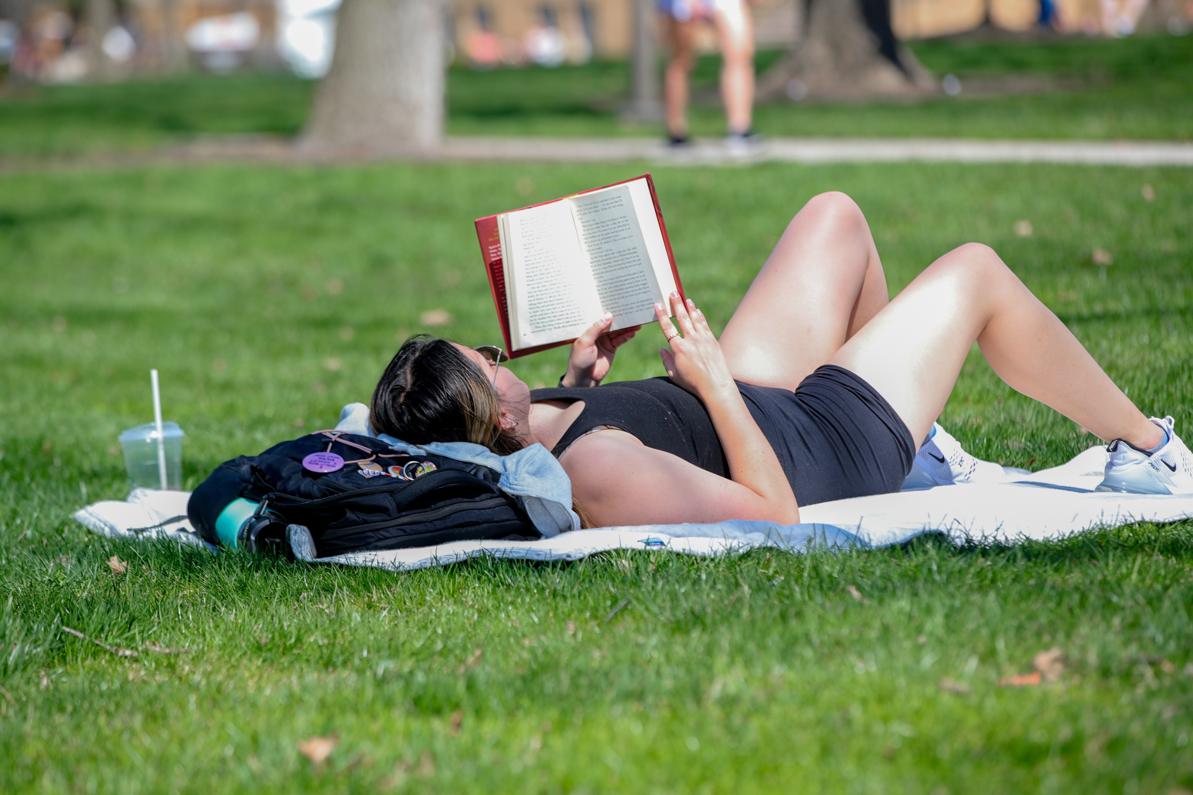 Student lays on her back reading a book on campus