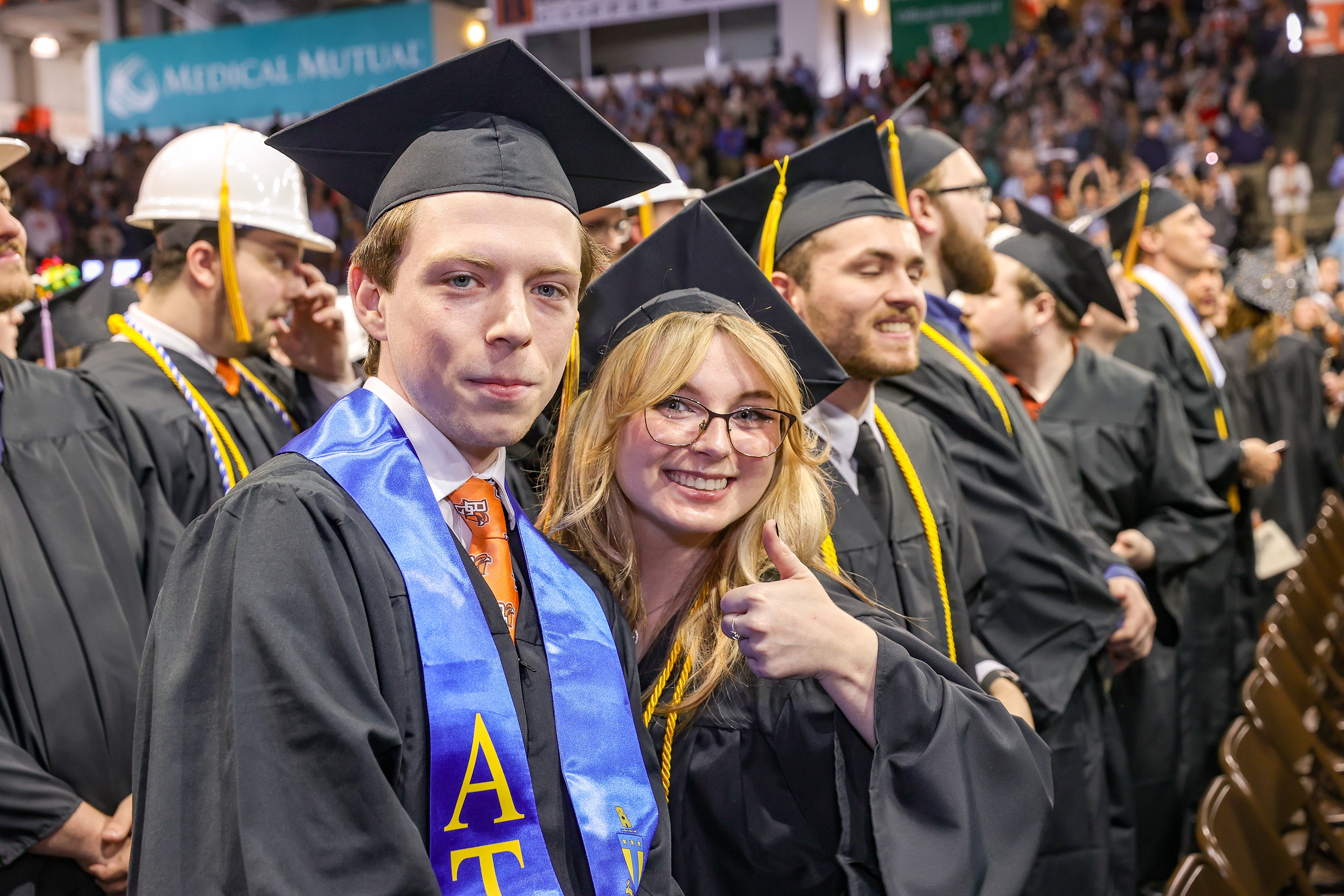 Two BGSU graduates pose with a thumbs up at graduation 