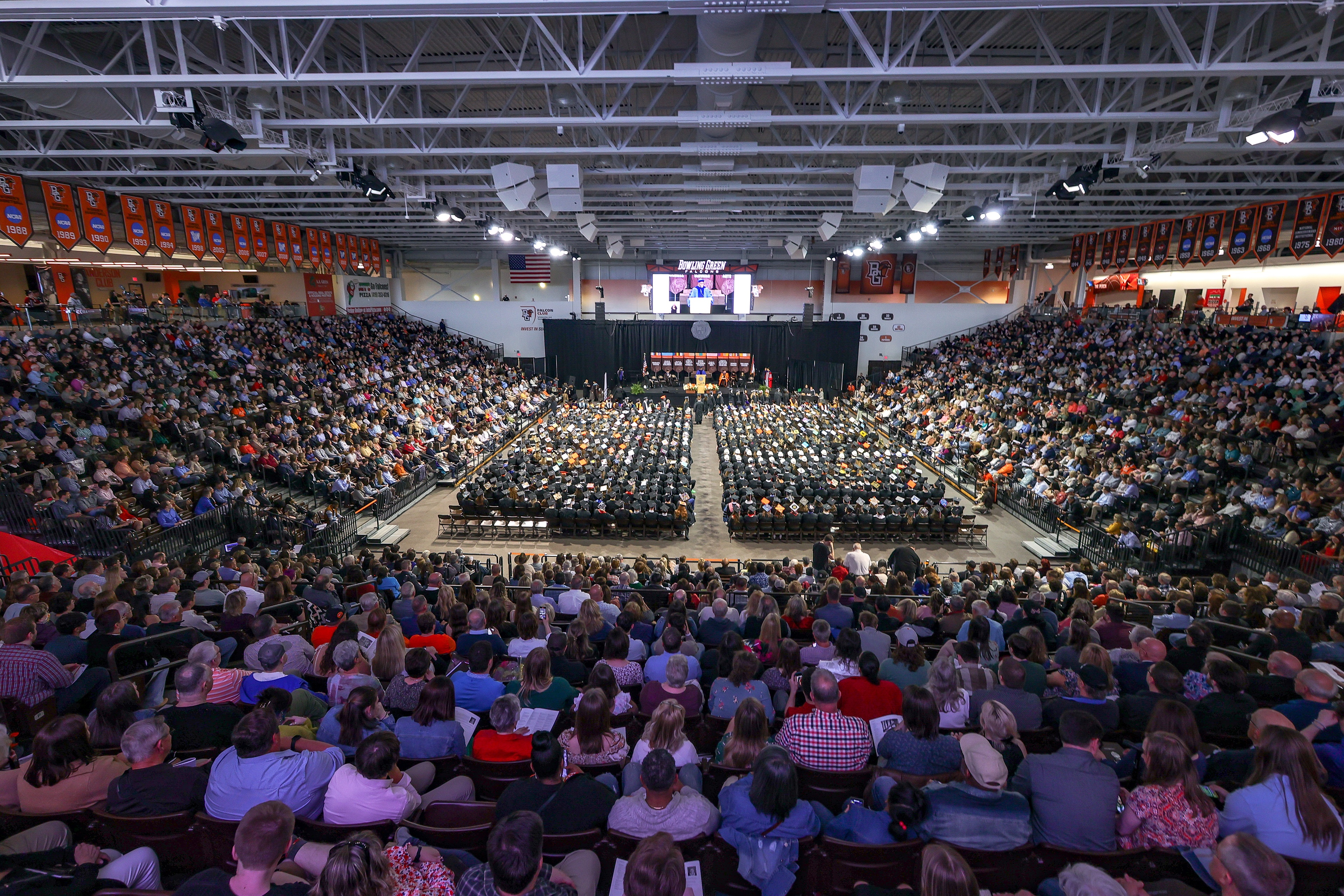 Stroh Center seats are filled with famiy and friends as 2023 graduates sit in chairs on the floor during Commencement