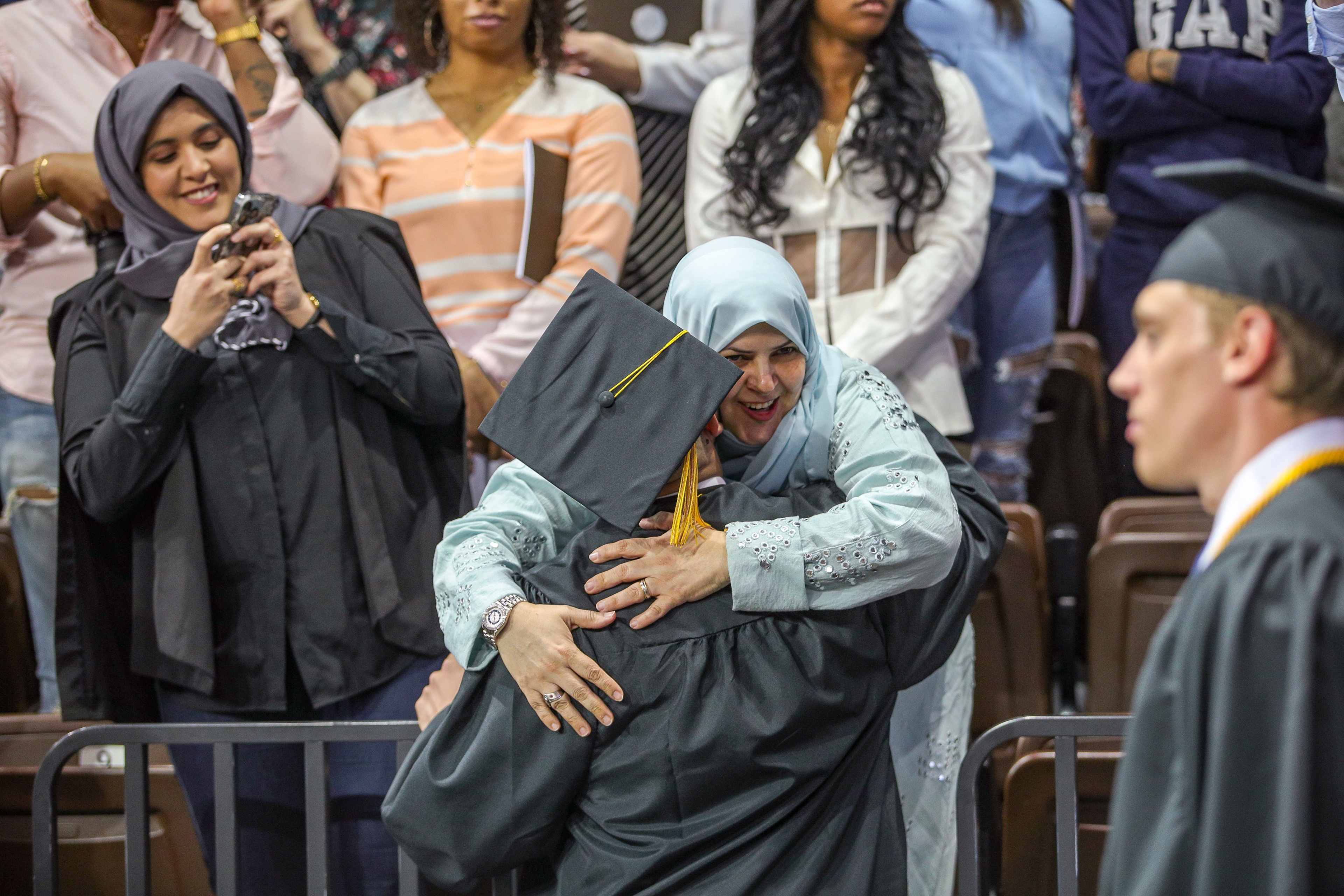 Woman in Stroh Center stands hugs graduate 
