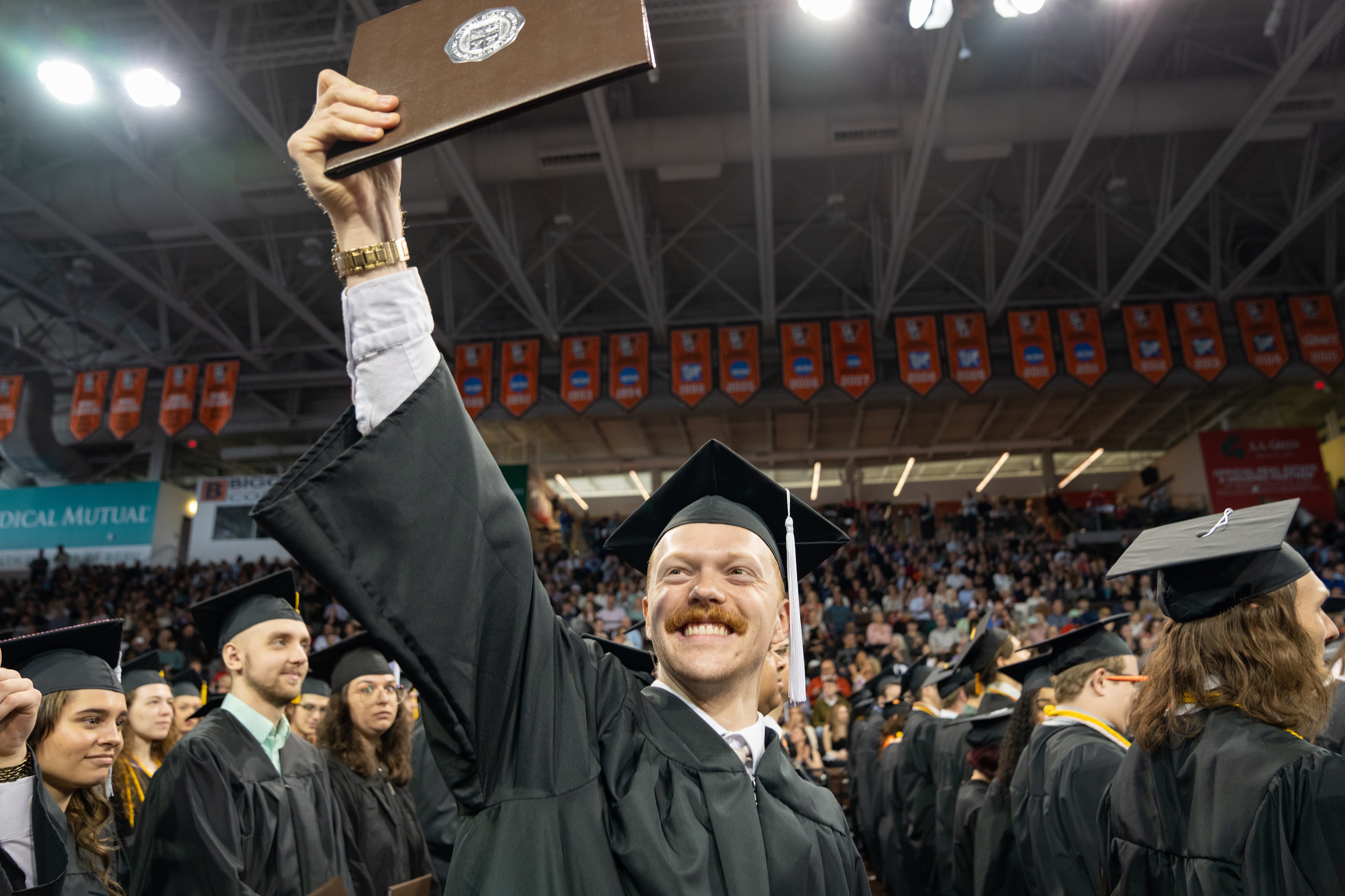 BGSU graduate holds up diploma cover and smiles 