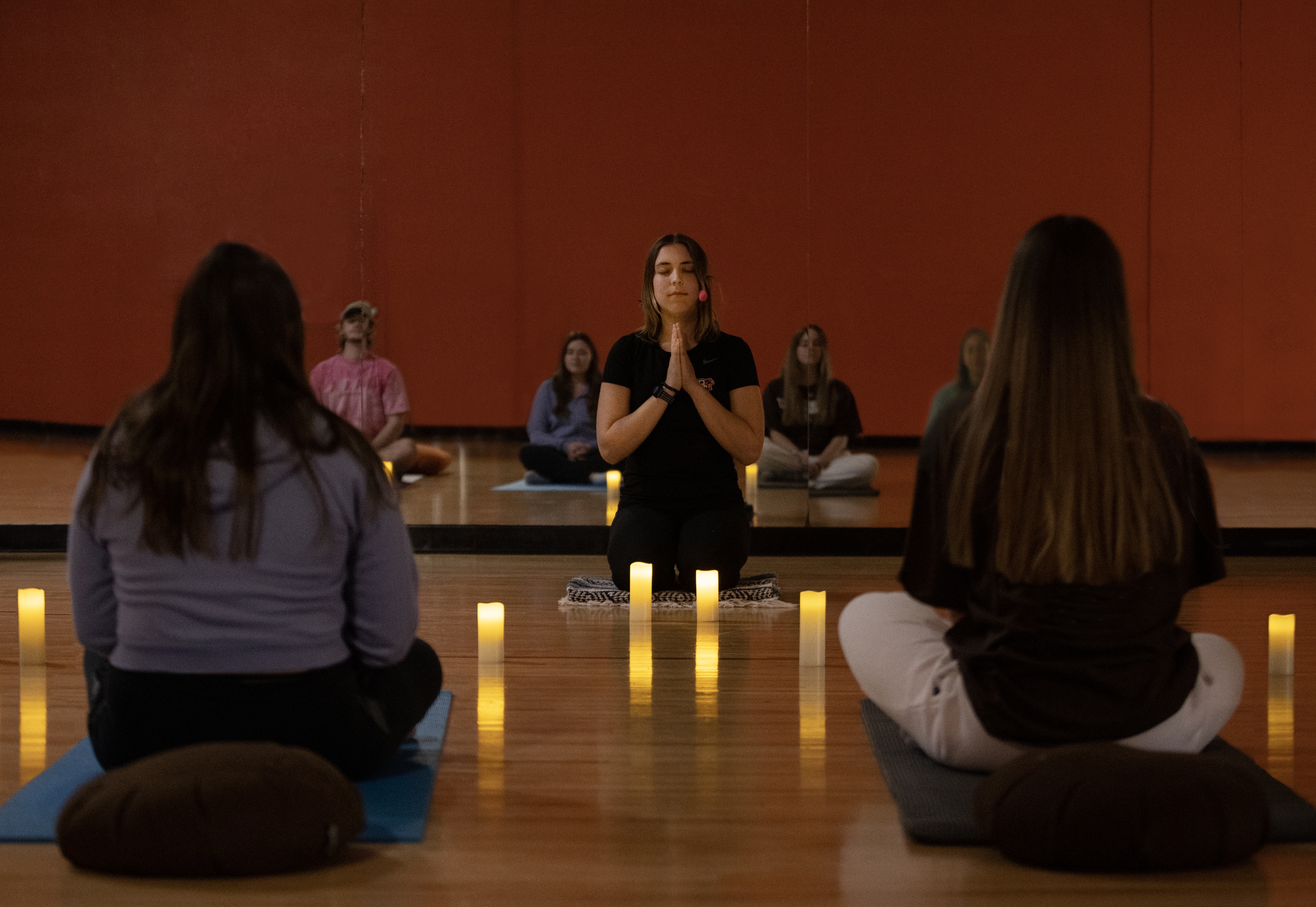 Woman clasps hands in front of her while leading students in meditation