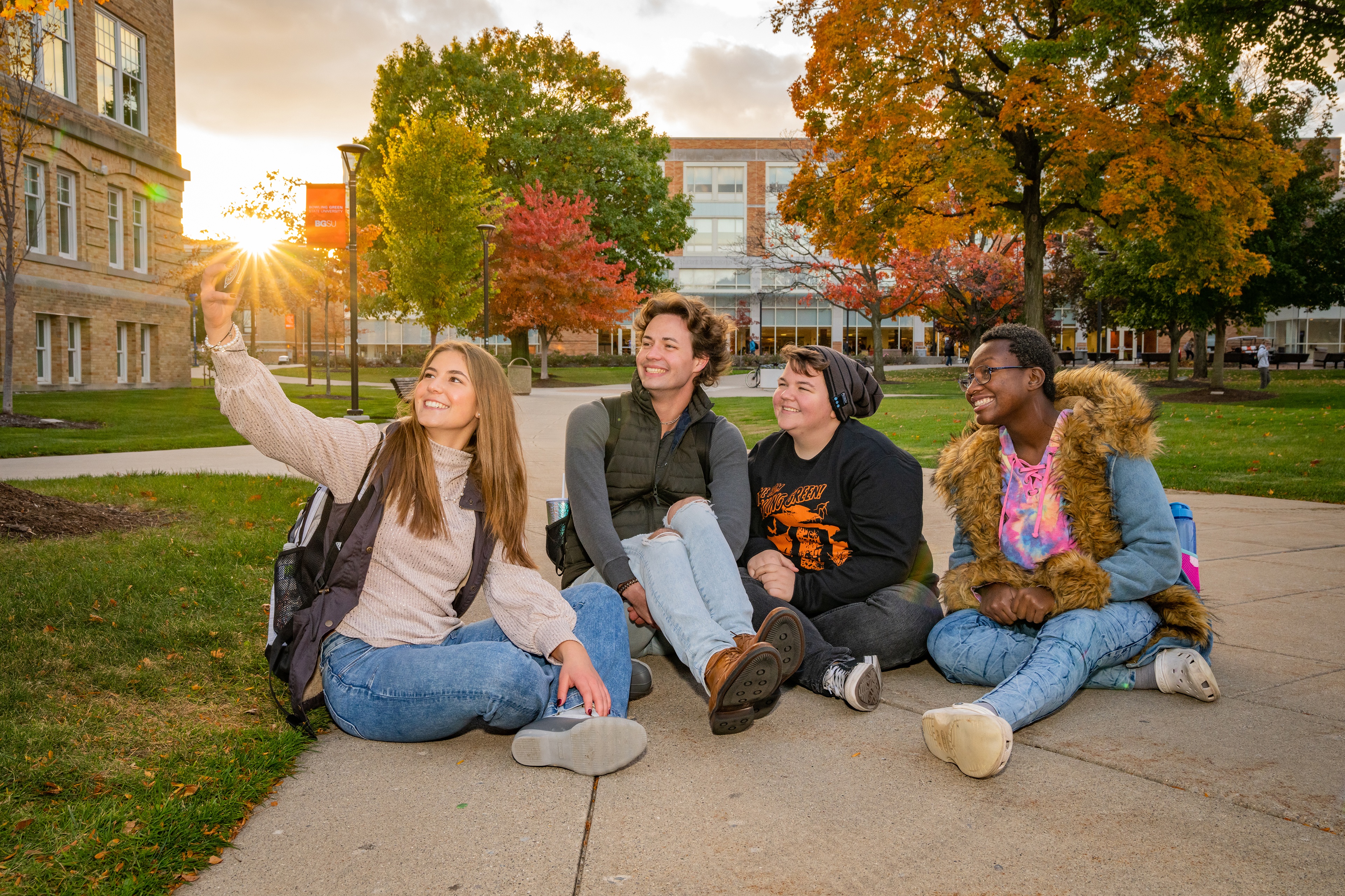 Four students smile for a selfie on campus