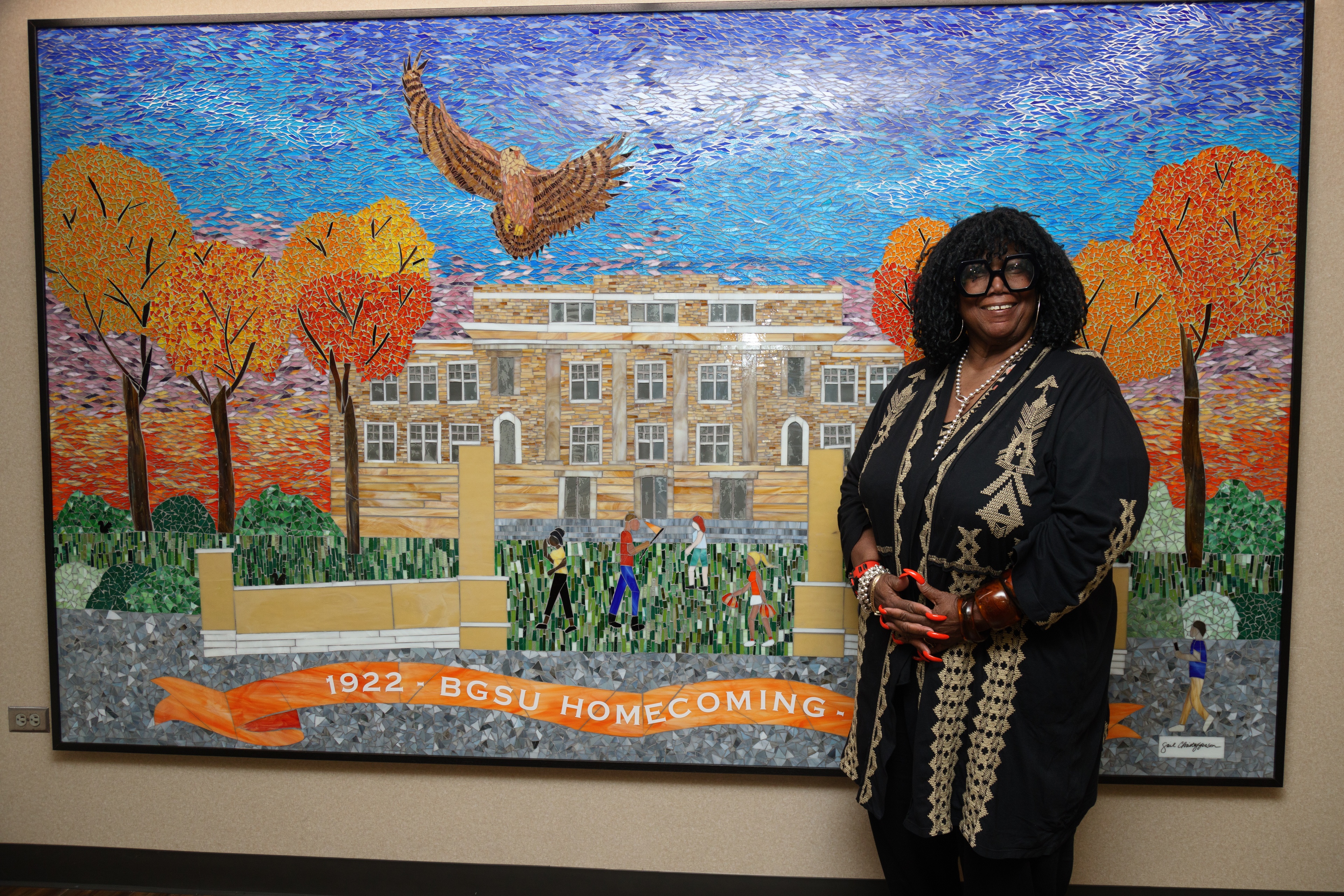 Woman stands in front of mural depicting Bowling Green State University
