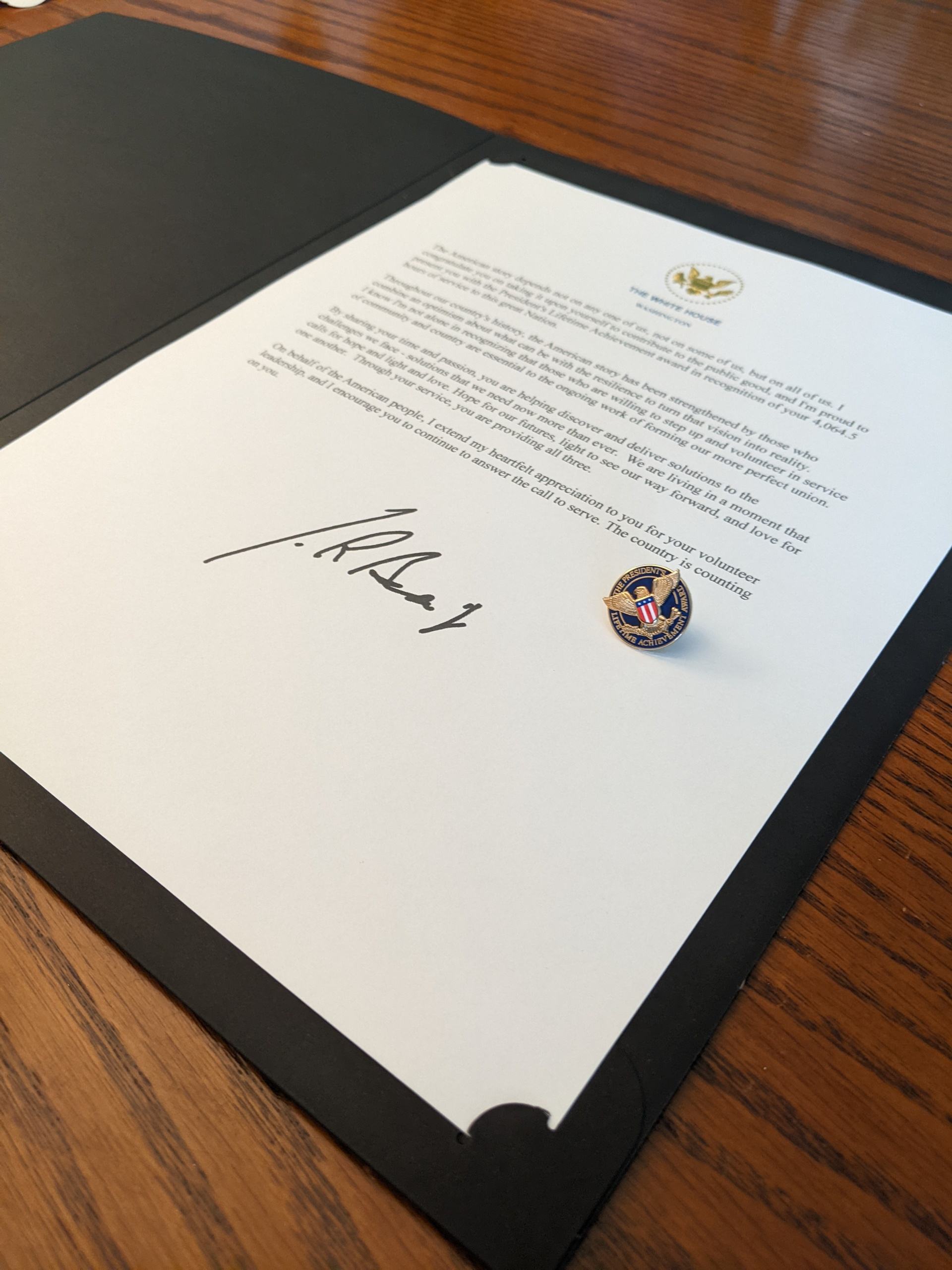 Letter signed by President Joe Biden and a pin given as part of the President's Volunteer Service Award.