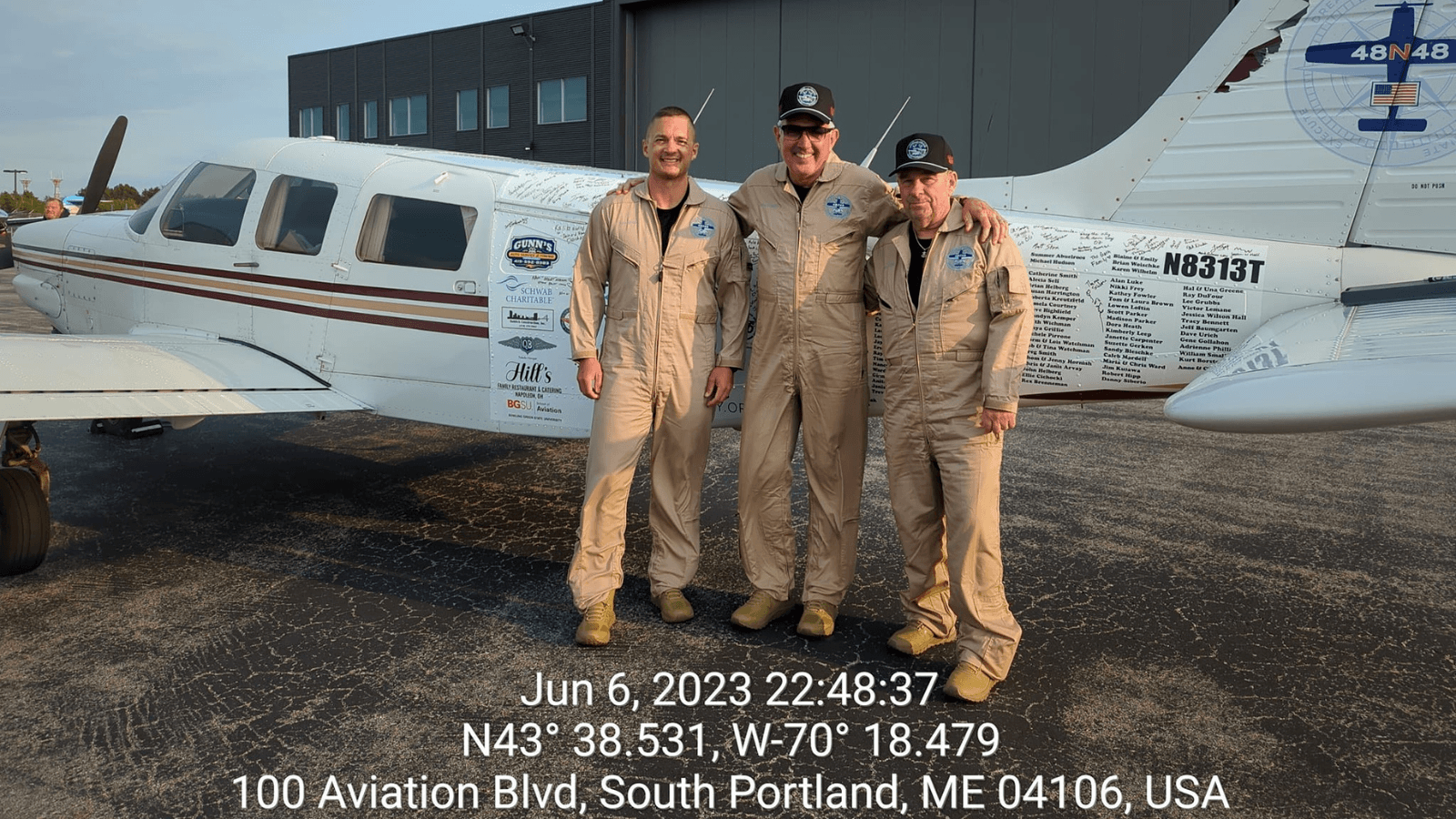 Three men stand in front of an airplane