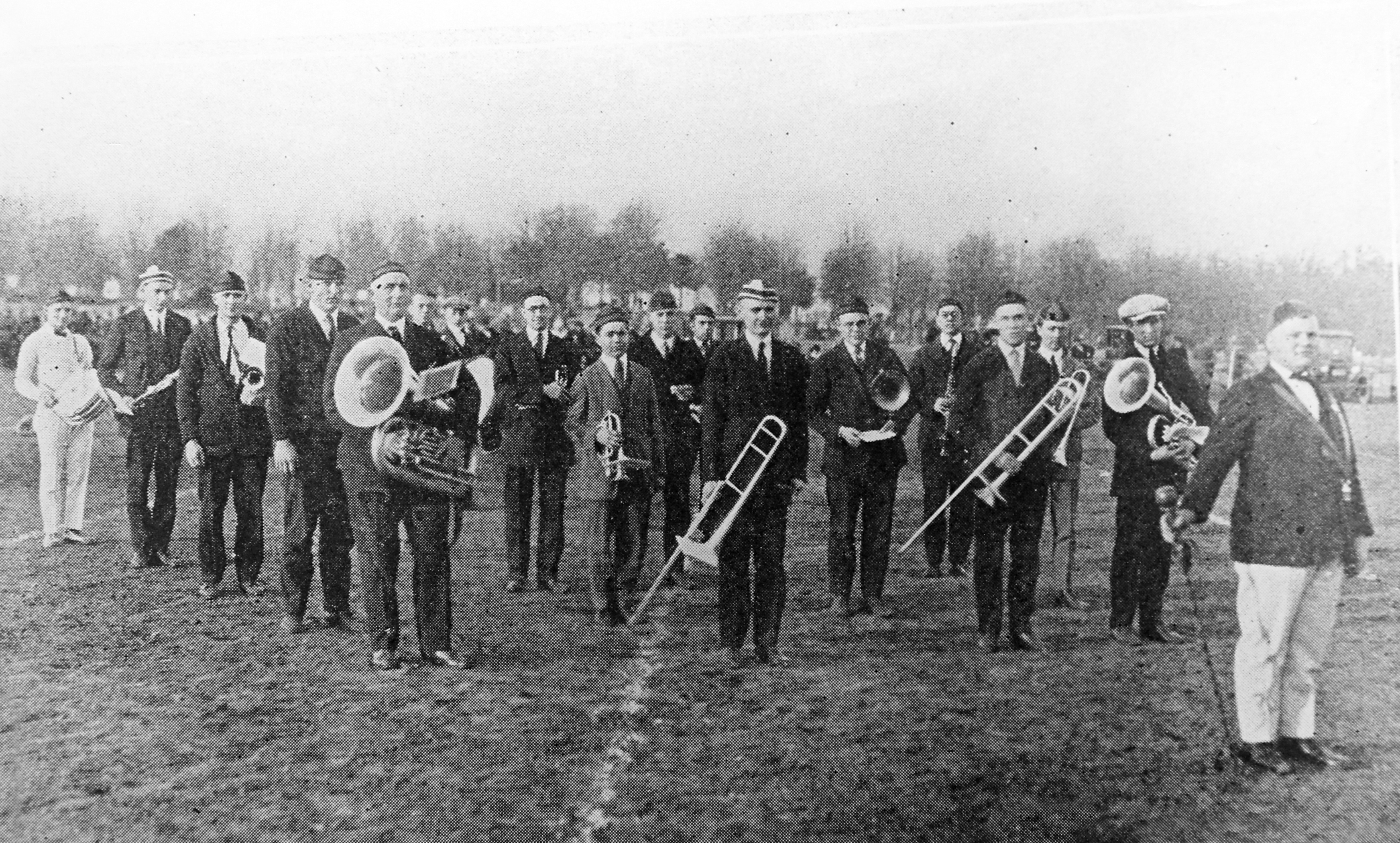 A group of 17 marching band musicians and a director stands on the field at Bowling Green State Normal College in 1923.