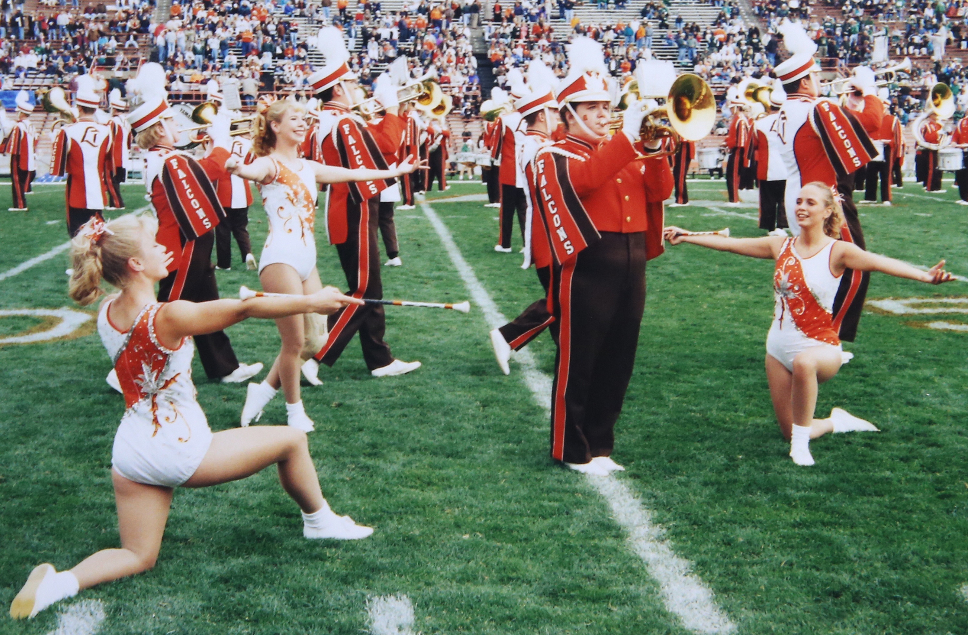 Three majorettes stand near a band member playing a mellophone 