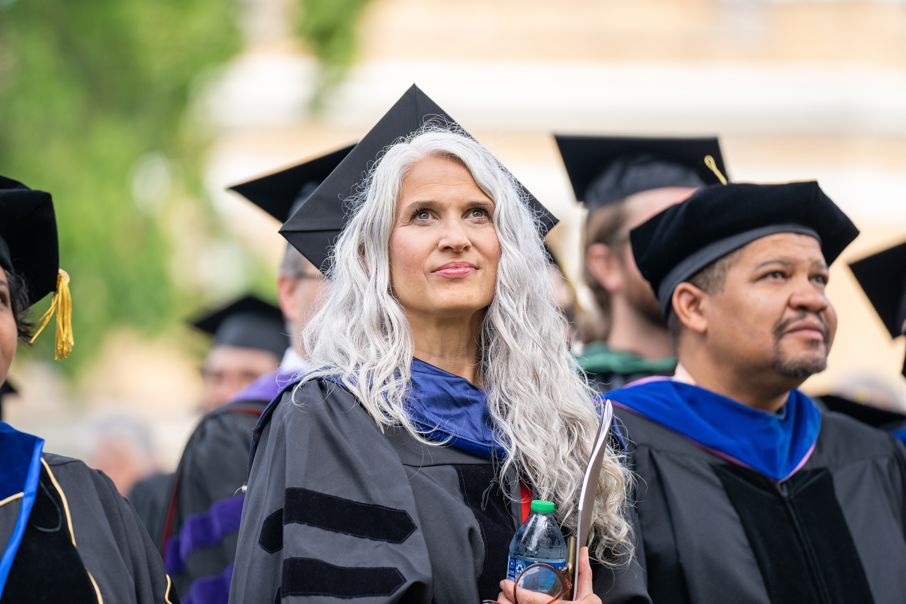 BGSU graduate with long white hair looks at the stage 