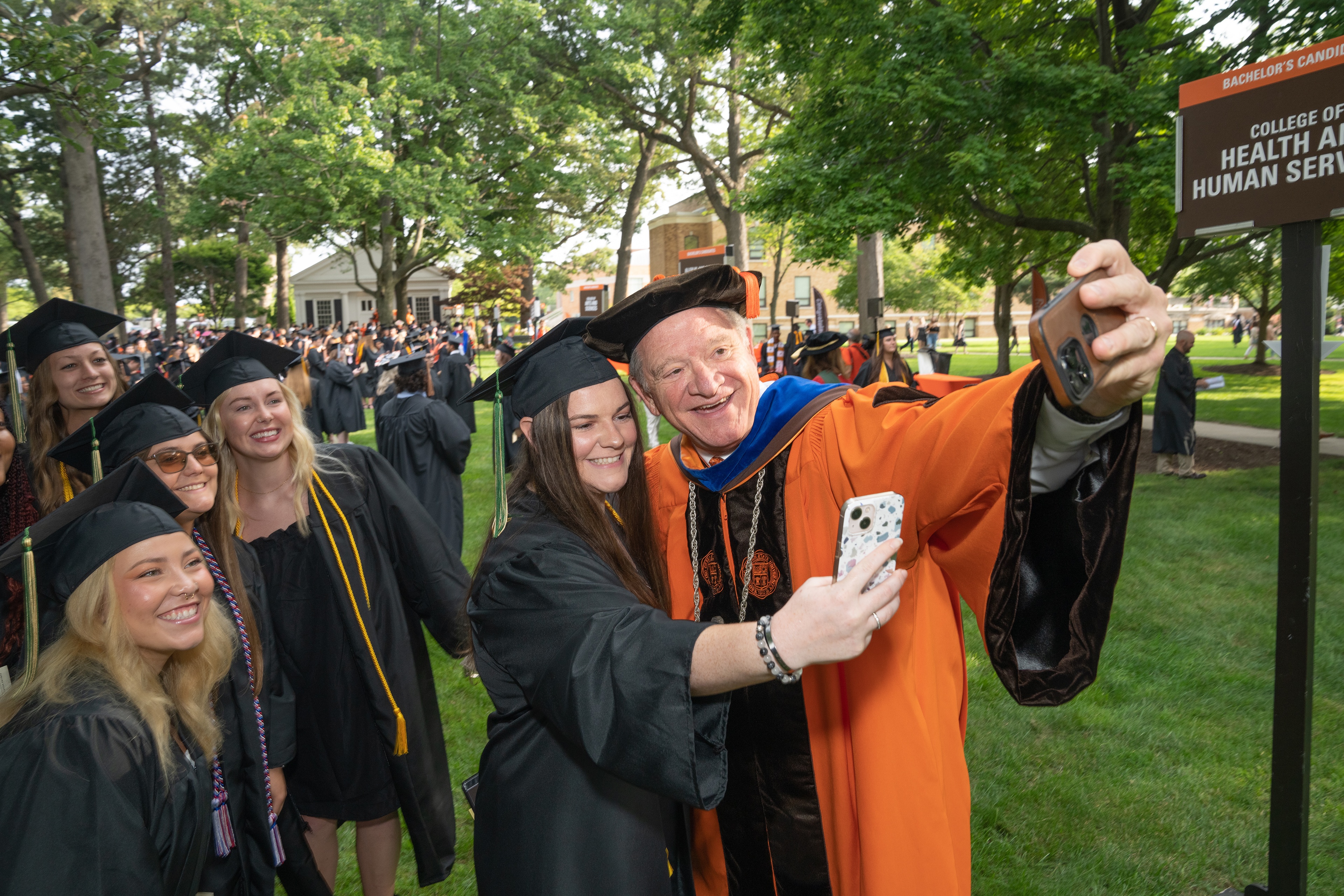 BGSU President Rodney K. Rogers takes a selfie with several graduates