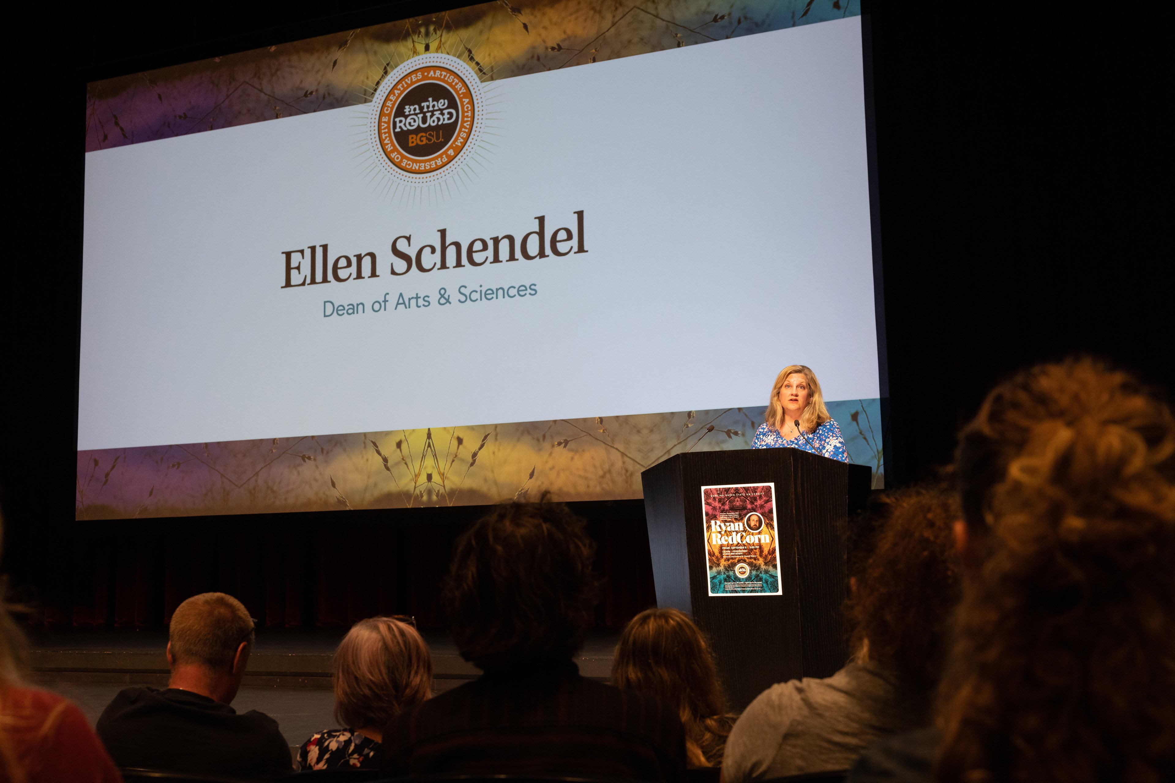 Ellen Schendel speaks at a podium at the Donnell Theatre. 