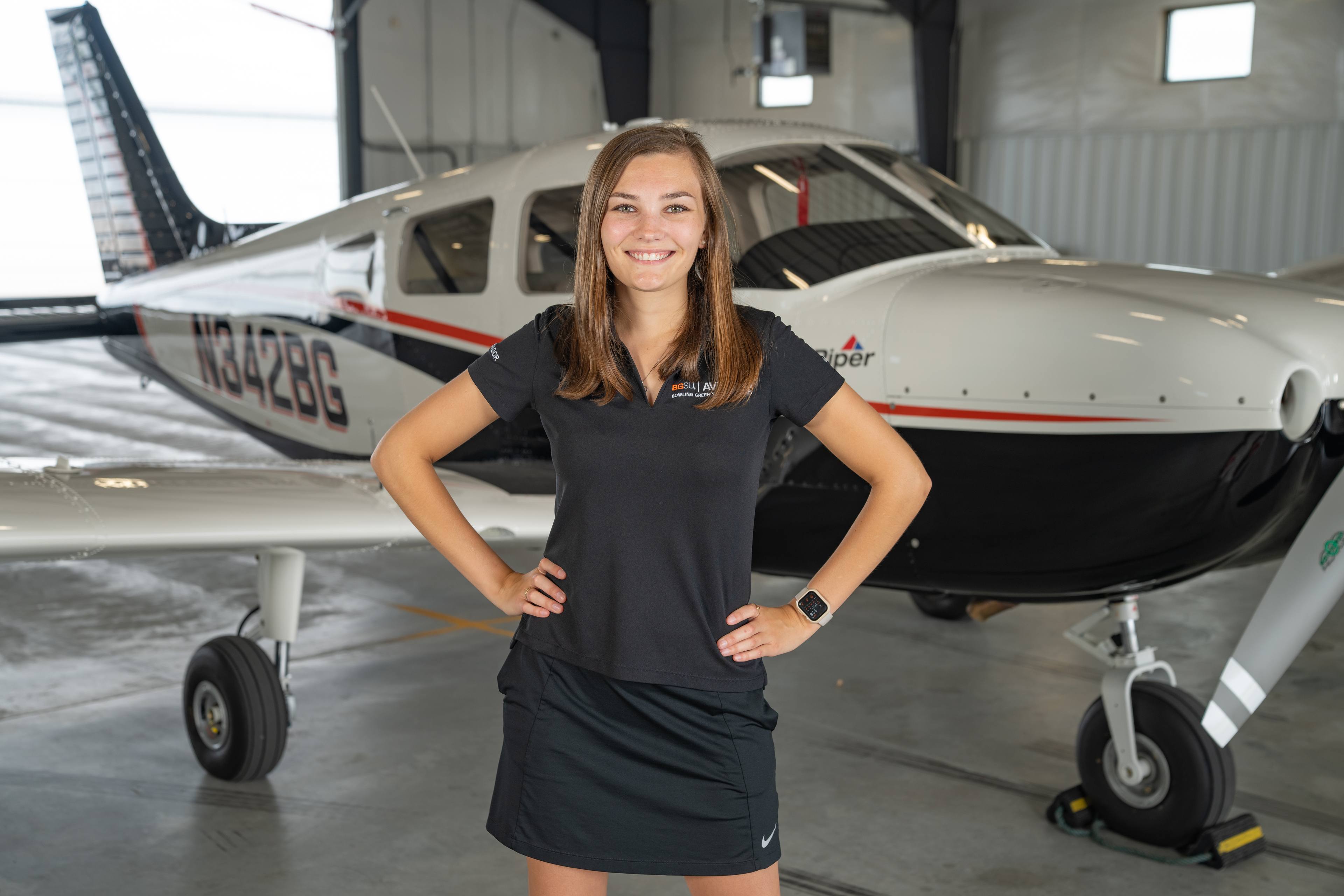 BGSU student Olivia Thornton poses in front of an airplane at the BG Flight Center.
