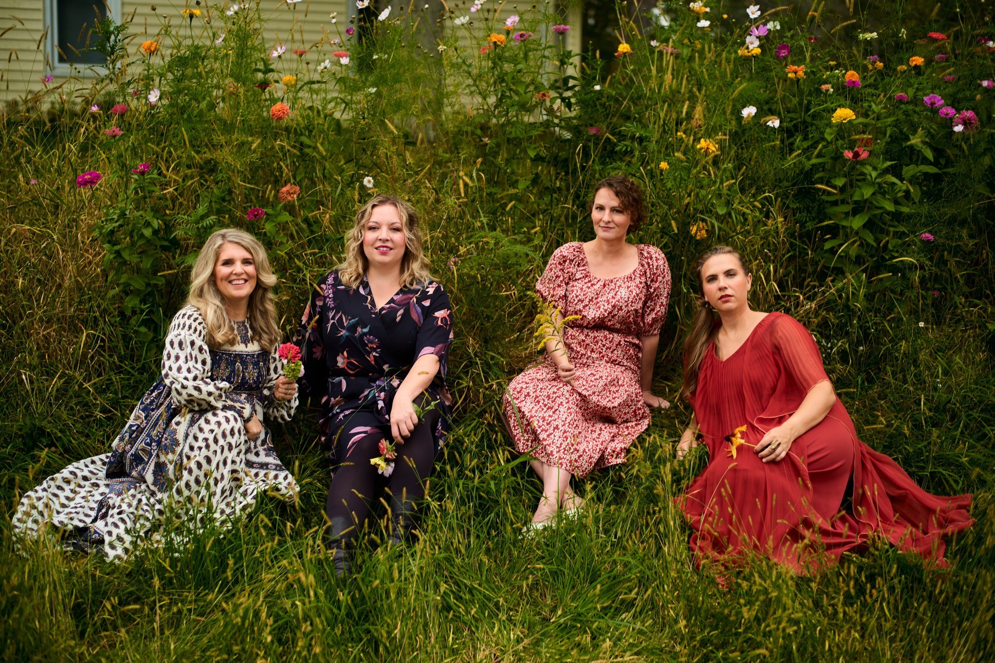 Four women who make up the Quince vocal quartet sit in a field 