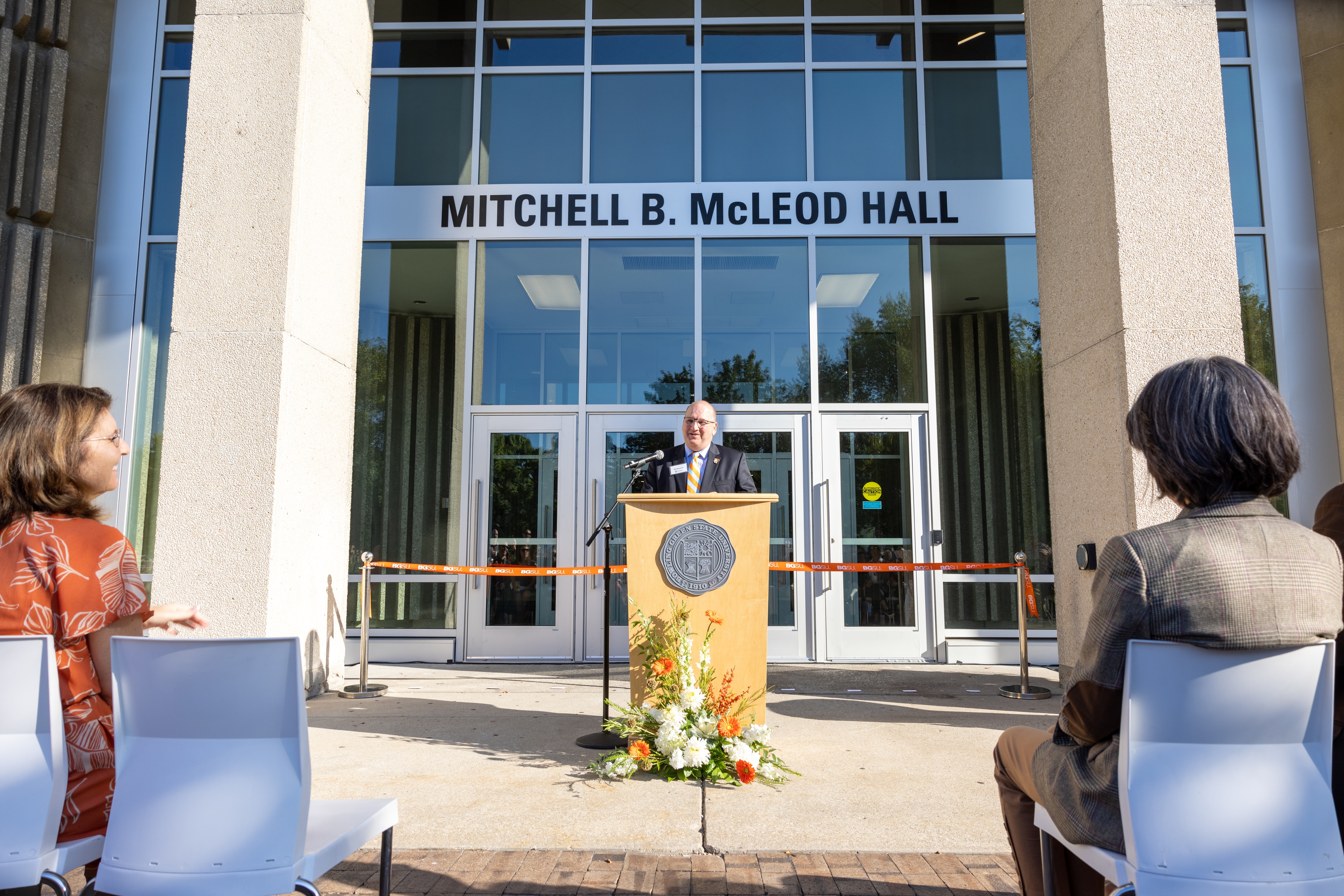 BGSU alumnus Mitchell B. McLeod speaks at a podium in front of McLeod Hall 