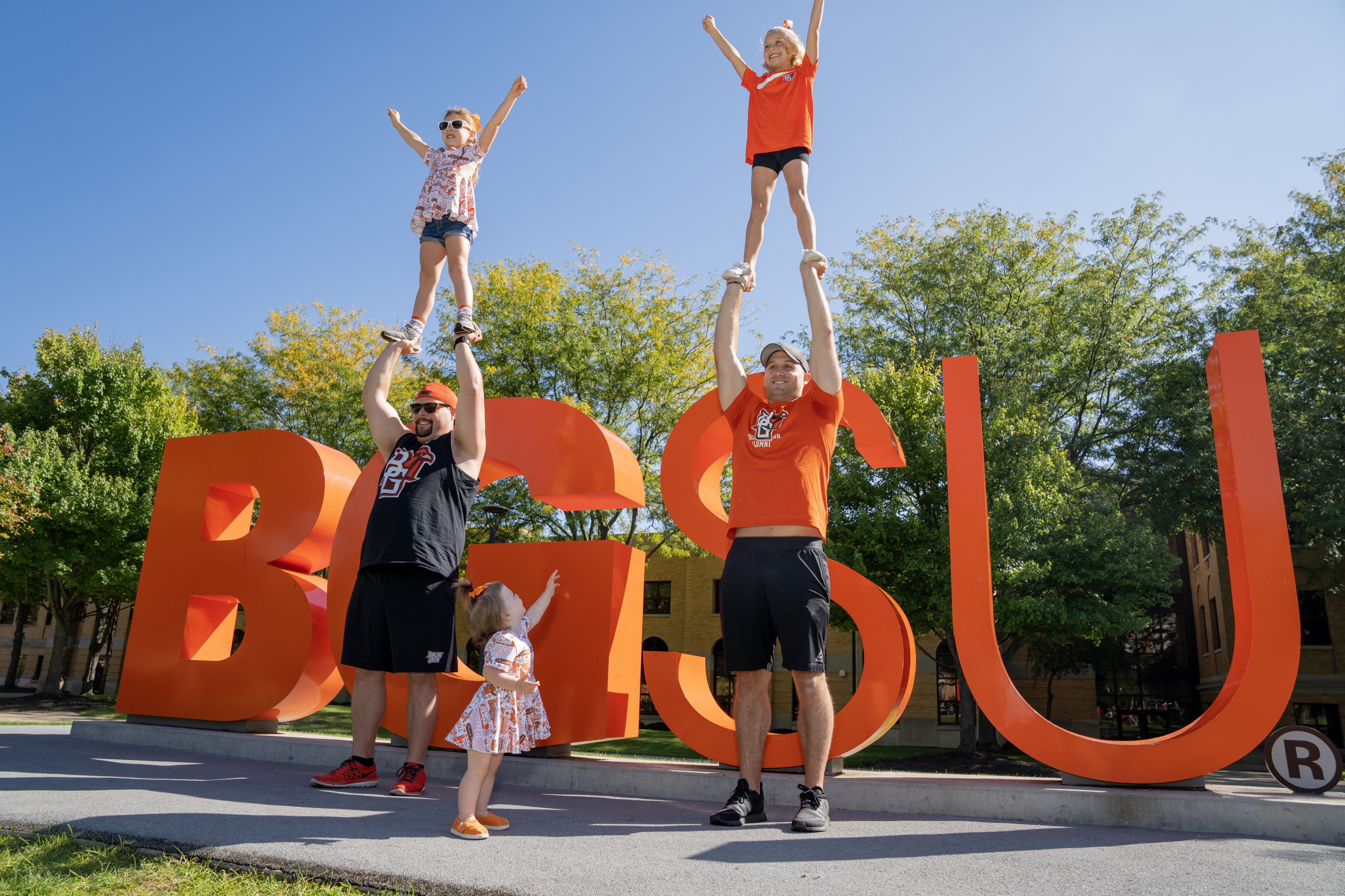 Falcon alumni lift their children in the air by the BGSU letters