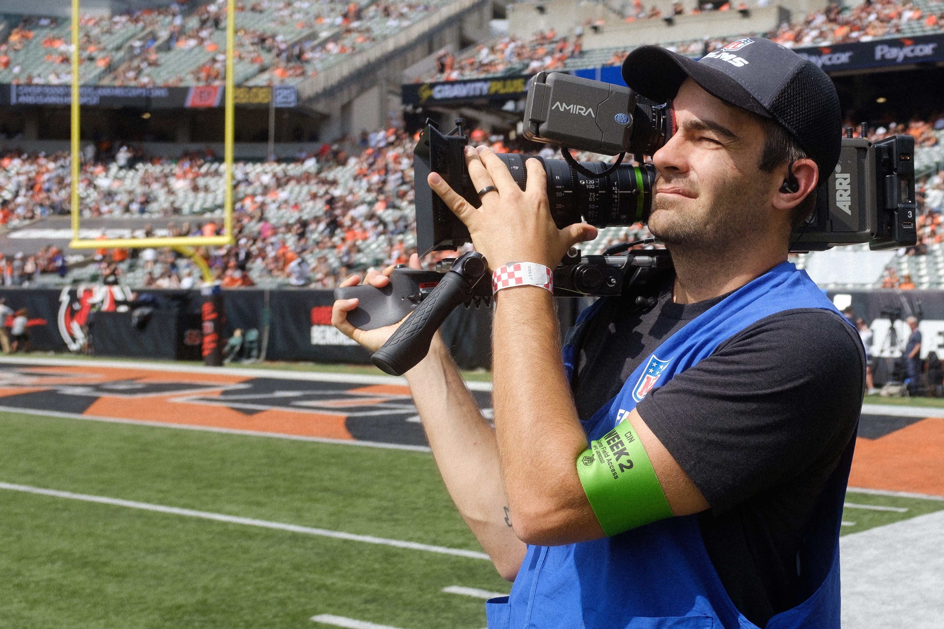 A person holding a video camera on an NFL sideline. 