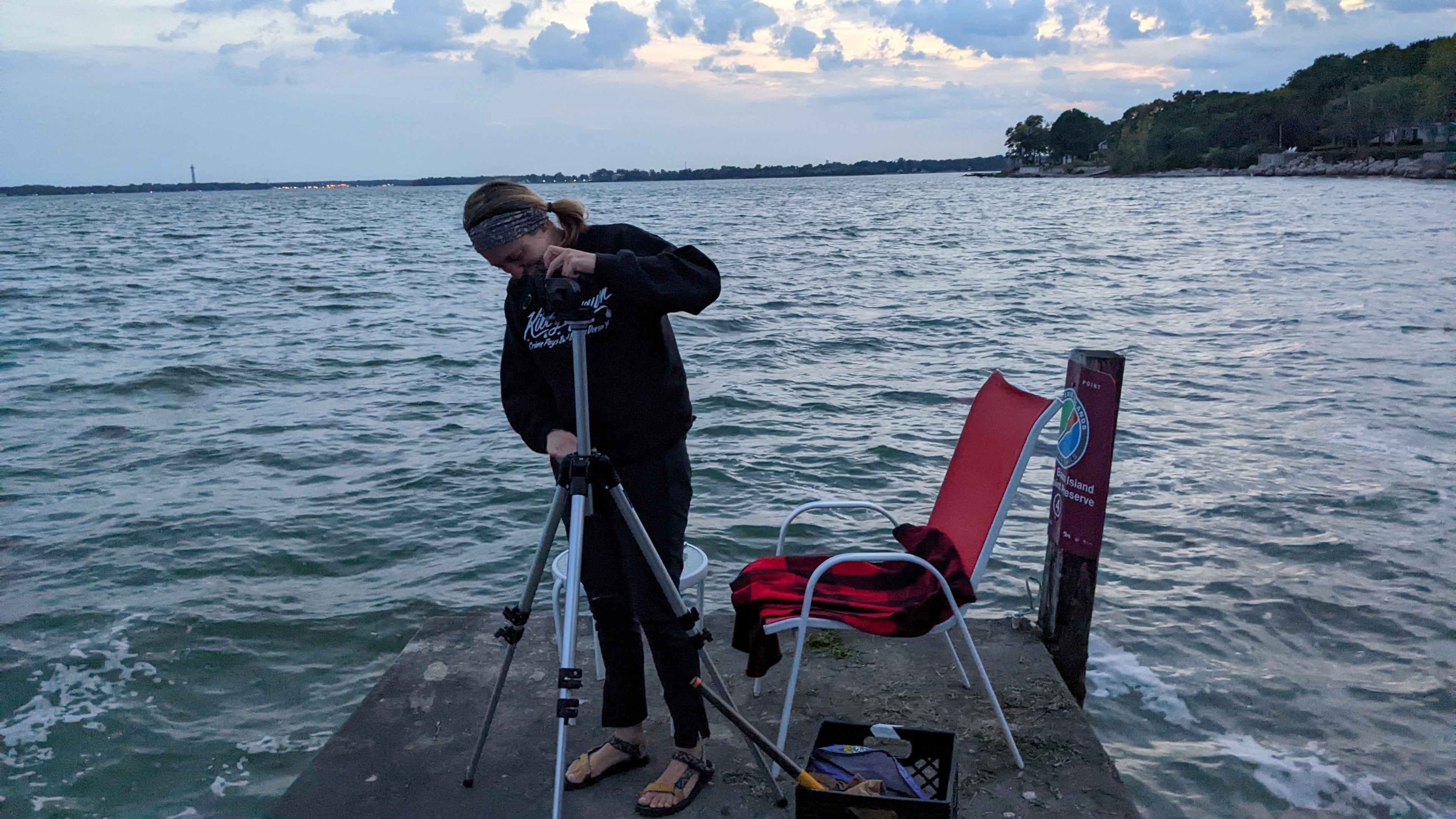 Woman setting up an infrared camera on Middle Bass Island overlooking Lake Erie.