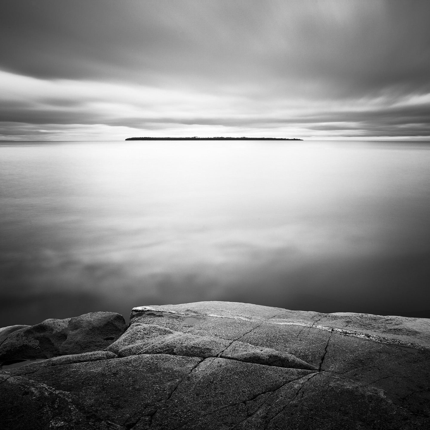 Black and white image of a faraway island, taken from a rocky outcrop