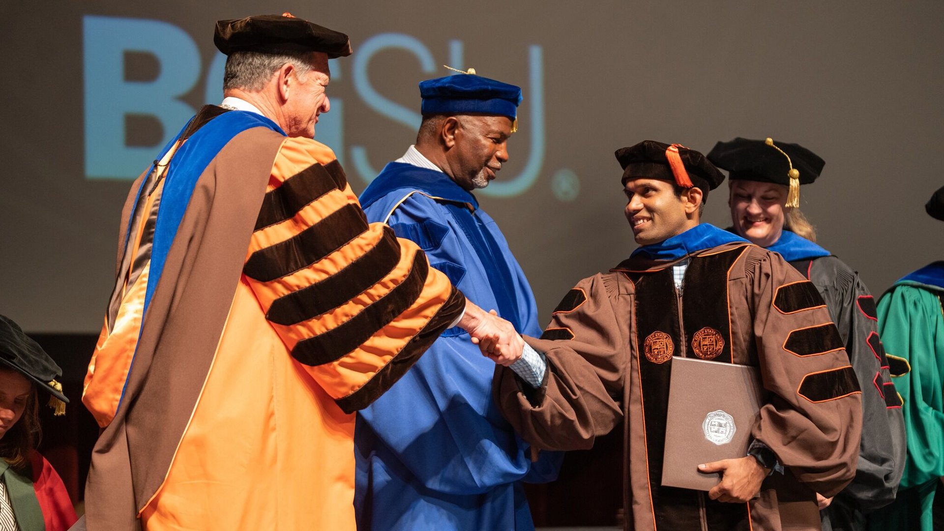 A BGSU graduate shaking hands with BGSU President Rodney K. Rogers.