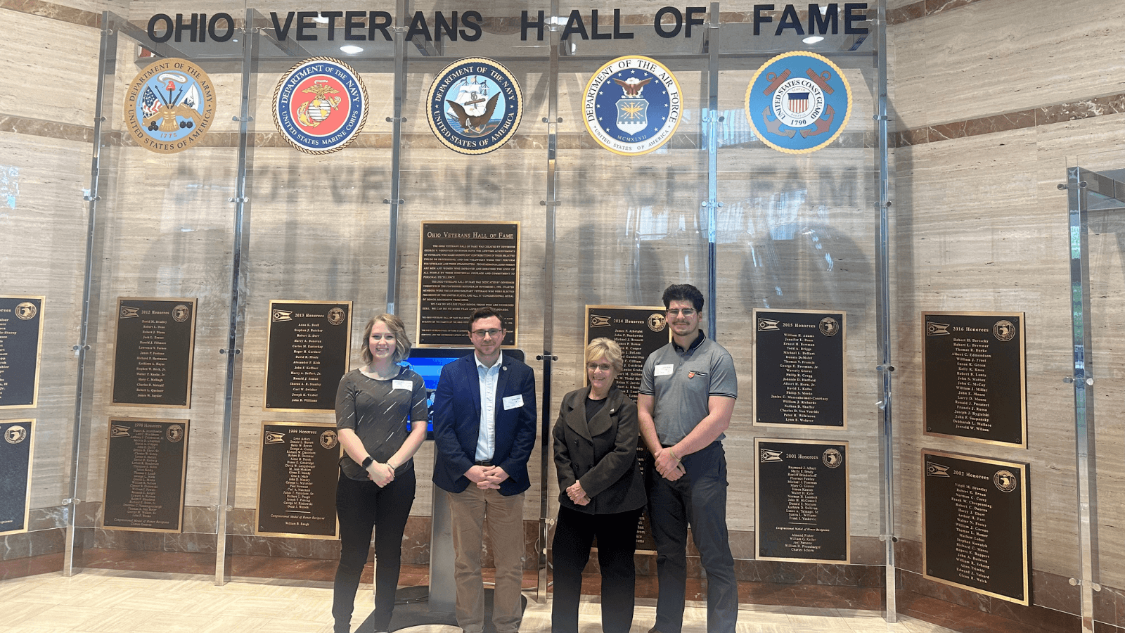 Four representatives of BGSU Military Student Services are pictured in front of signage for the Ohio Veterans Hall of Fame in Columbus. 