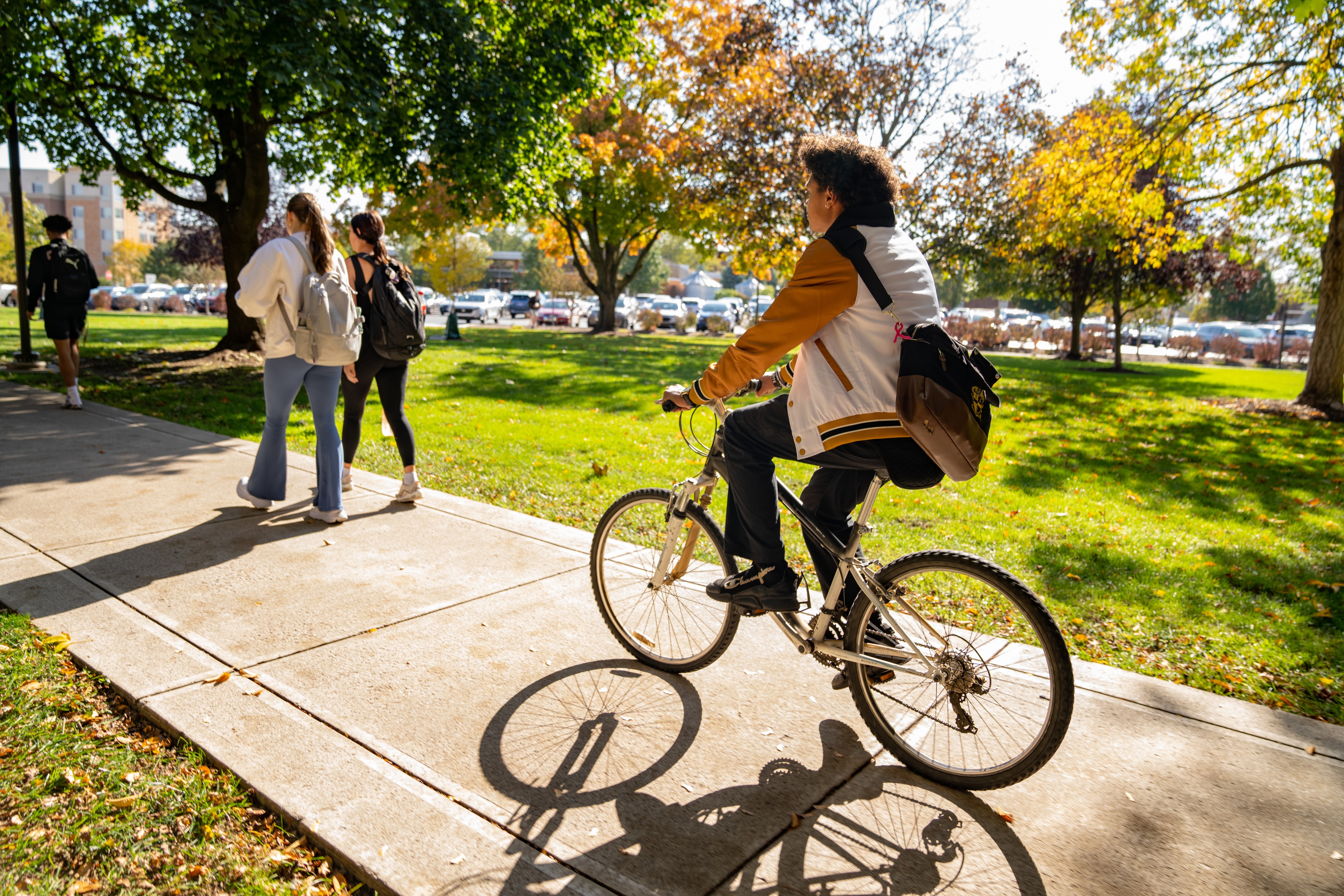 A person rides a bike on campus in the fall