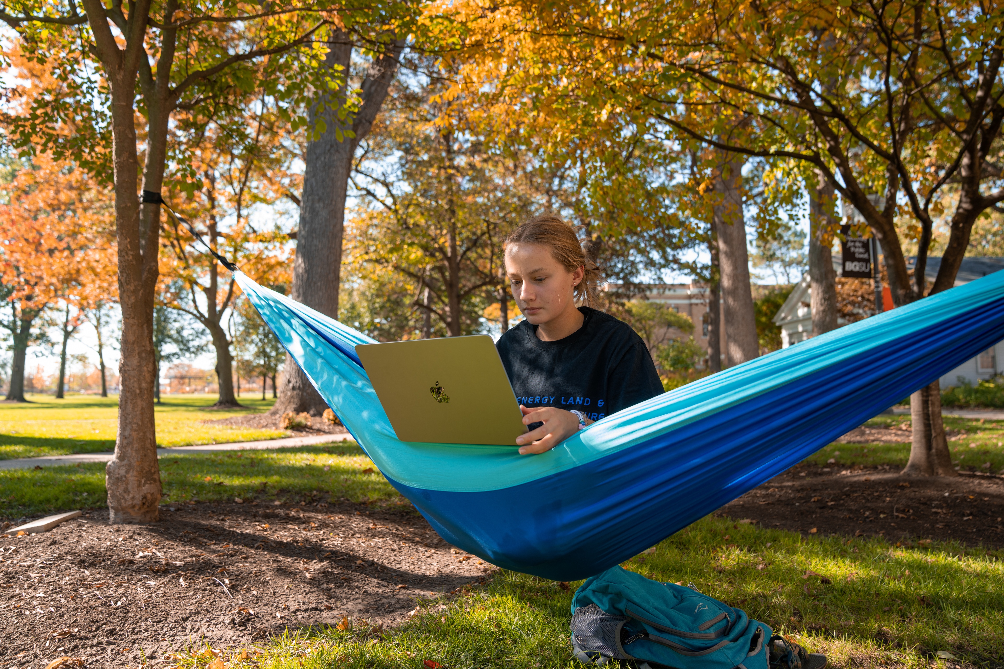 Female student sits in a blue hammock with a laptop on the BGSU campus