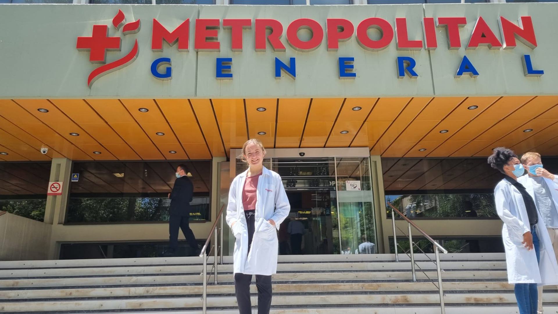A BGSU student stands in front of a hospital entrance in Athens, Greece.