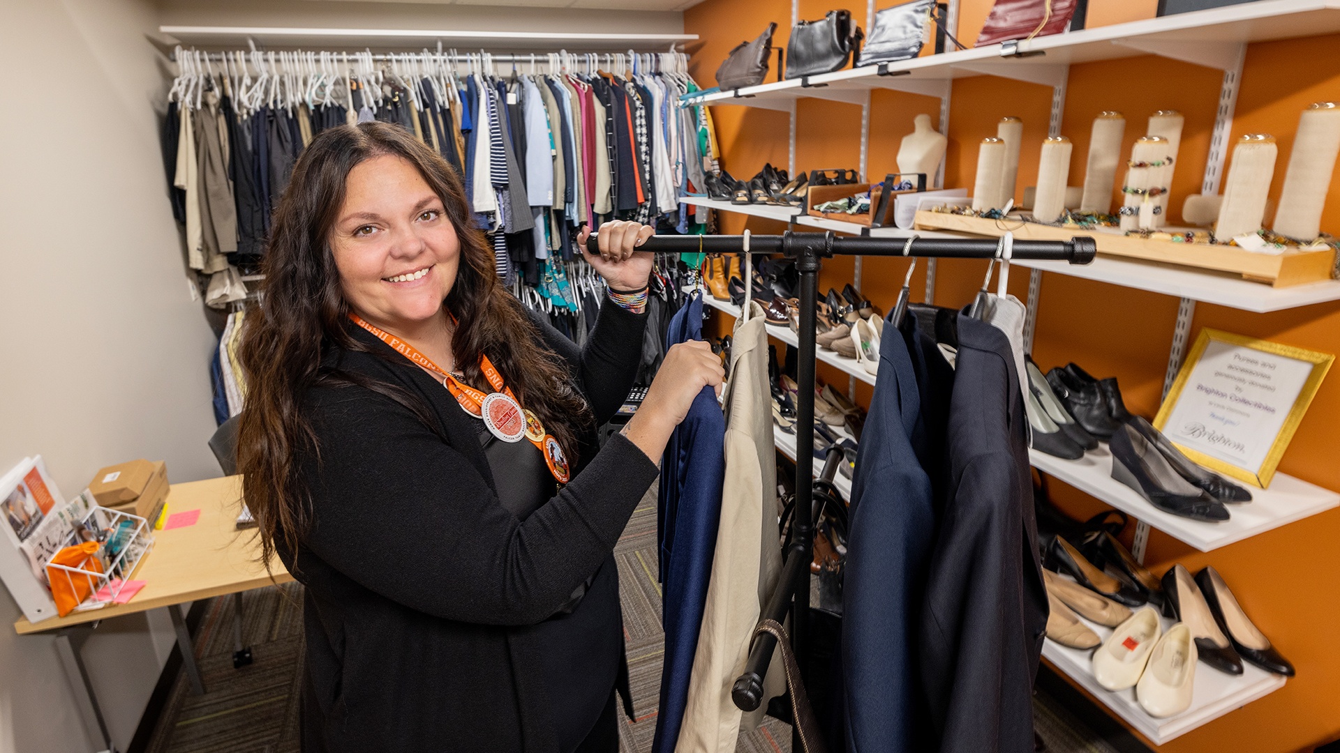 BGSU graduate student Tiffany Eckert smiles in front of racks of clothing at Mr. Agne's Career Collection.