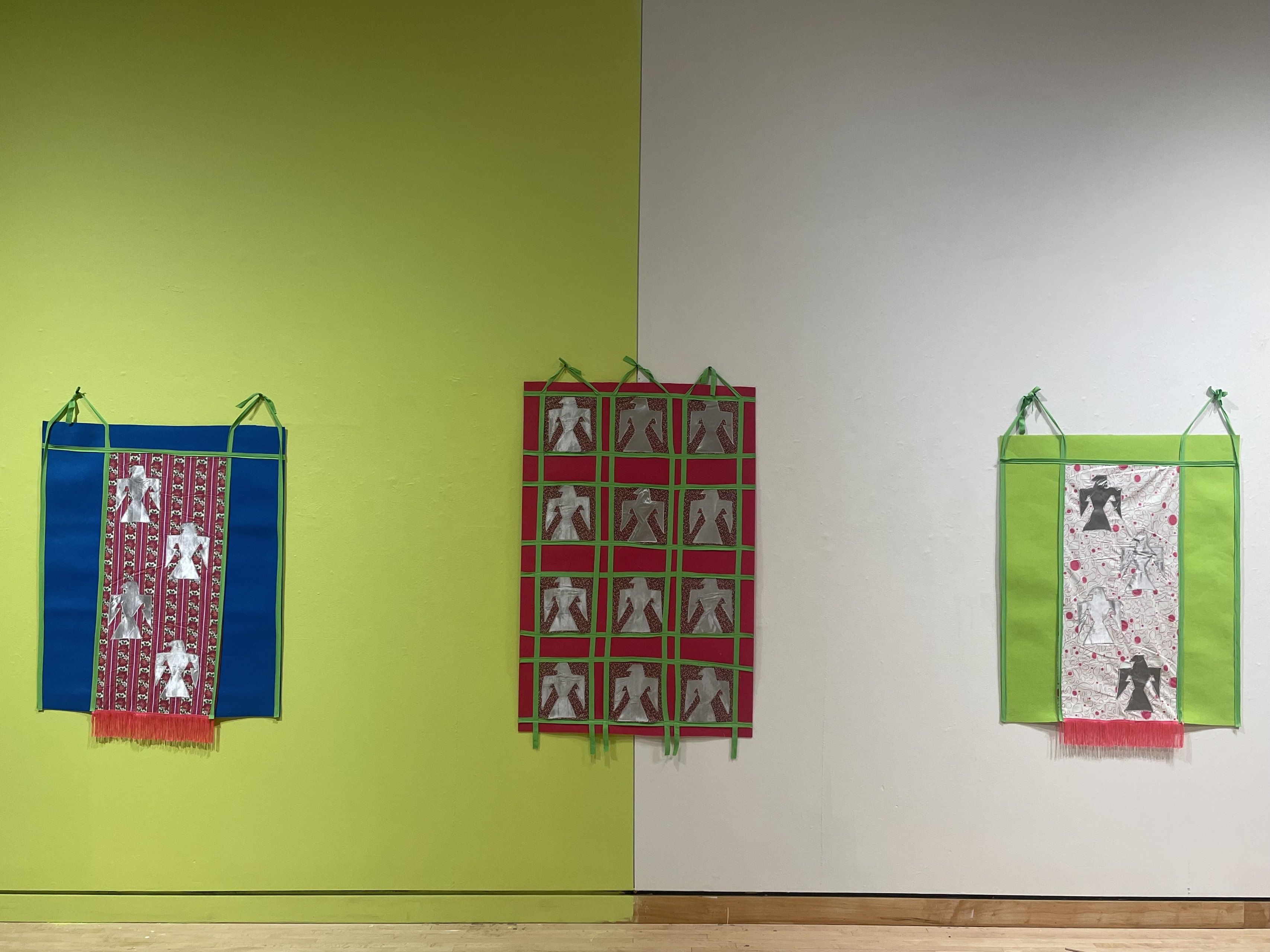 Three wall hangings by artist Emily Riddle show Native American Thunderbird iconography 