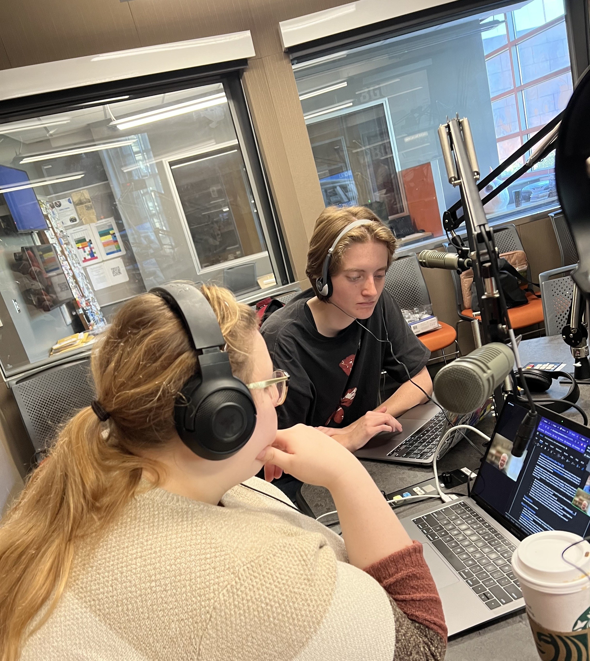Two BGSU students wearing headphones record a podcast.