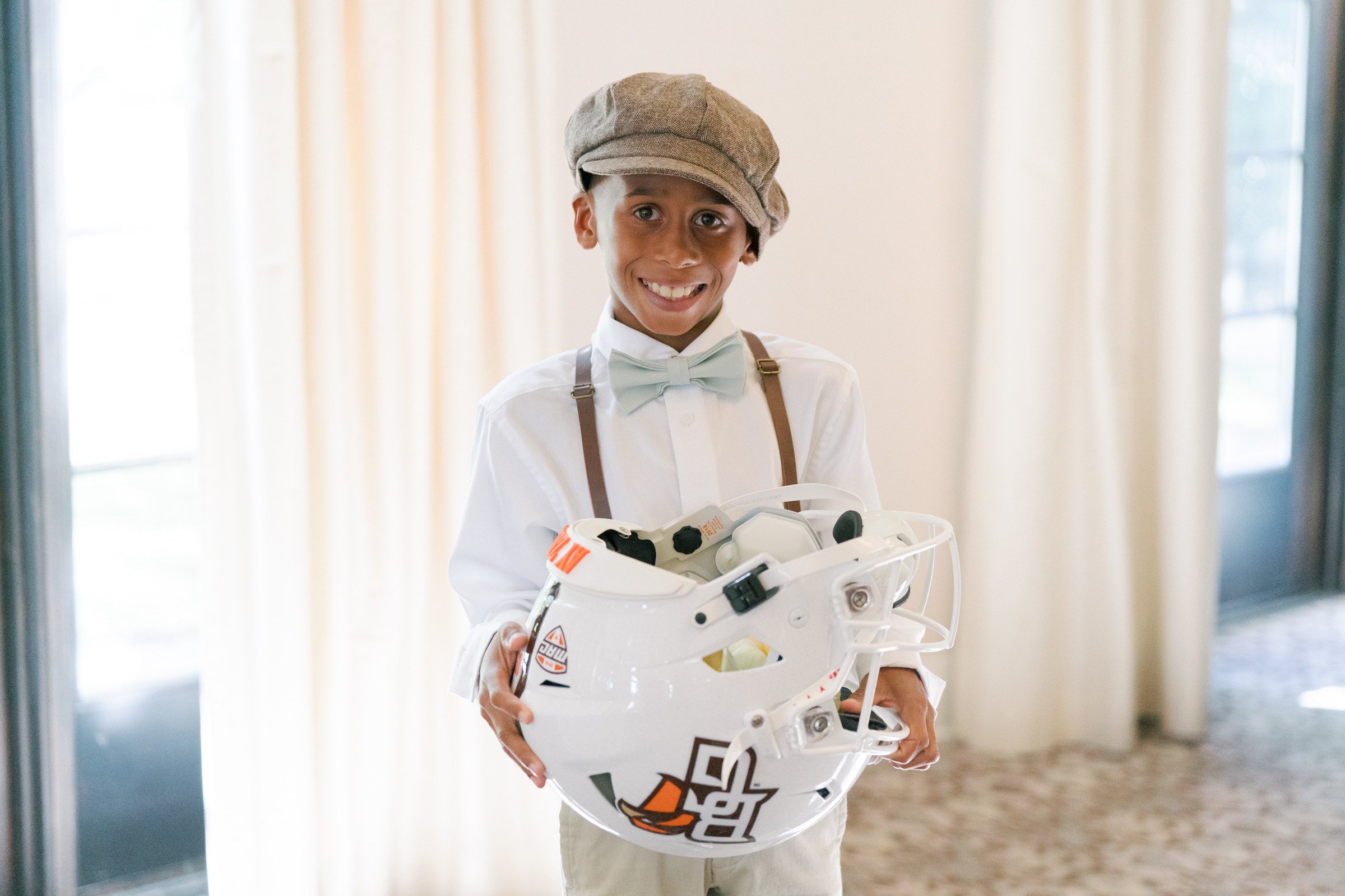 A child holding a white BGSU football helmet 