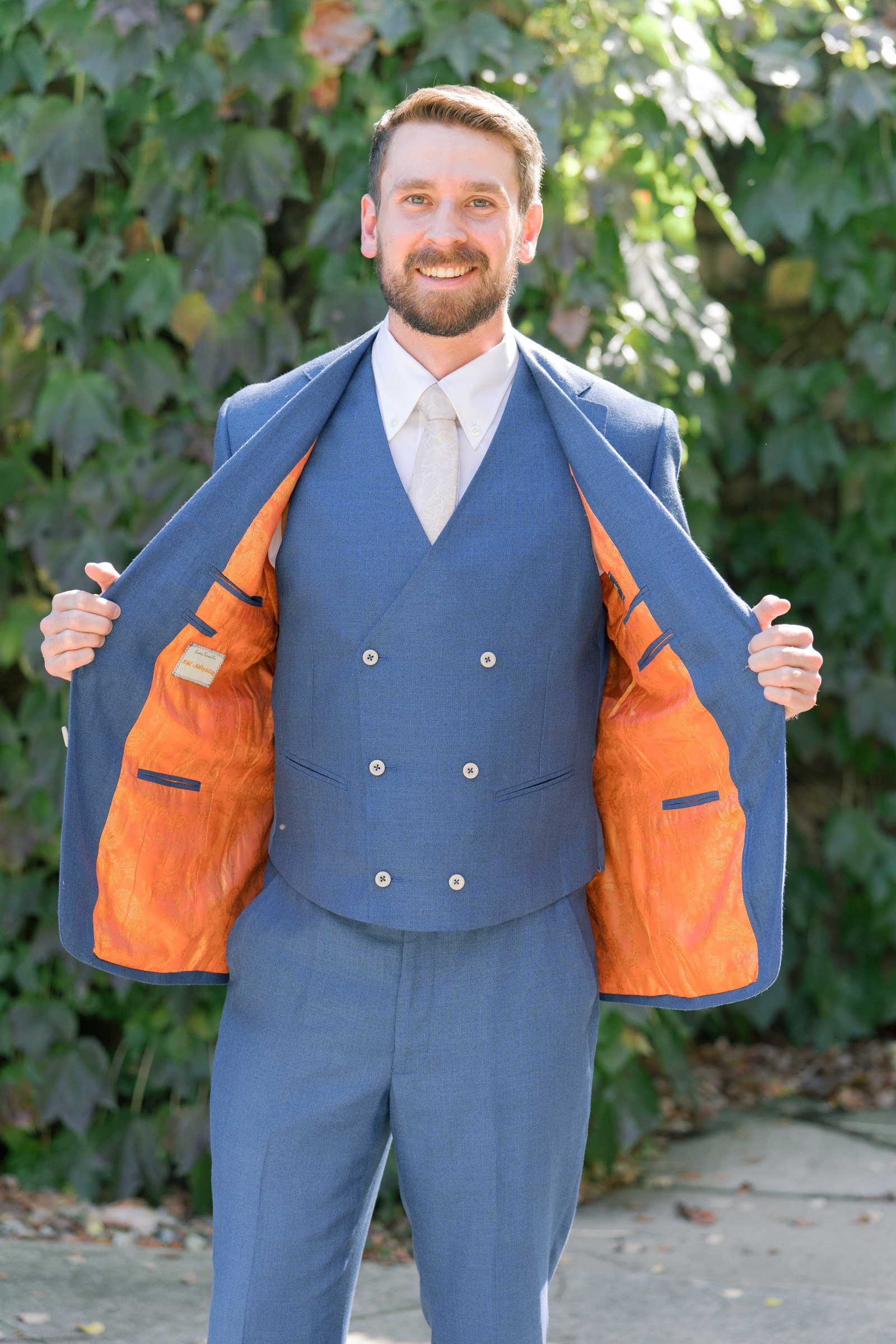 Kohl Tabener holds his suit jacket open to show the orange fabric inside