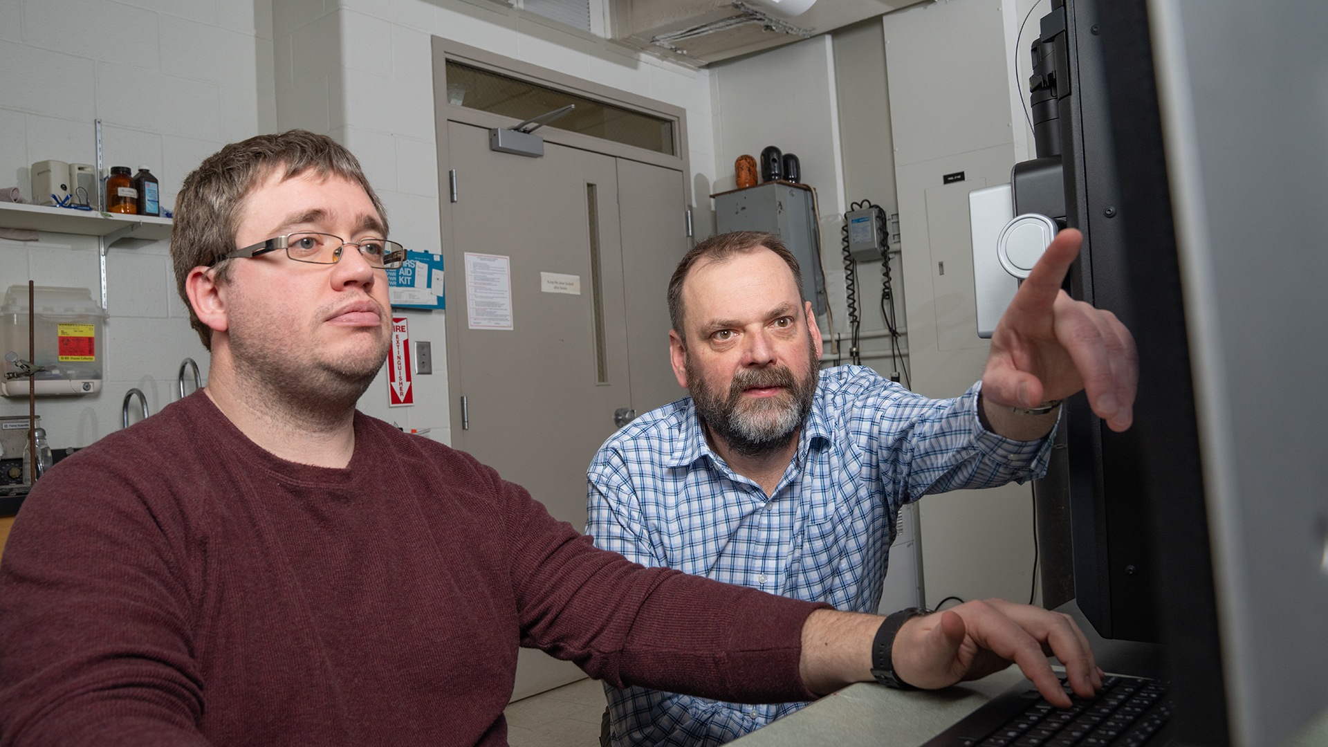 Dr. James Metcalf and Dr. Joe Furgal discuss spectrometer results at a desktop computer.