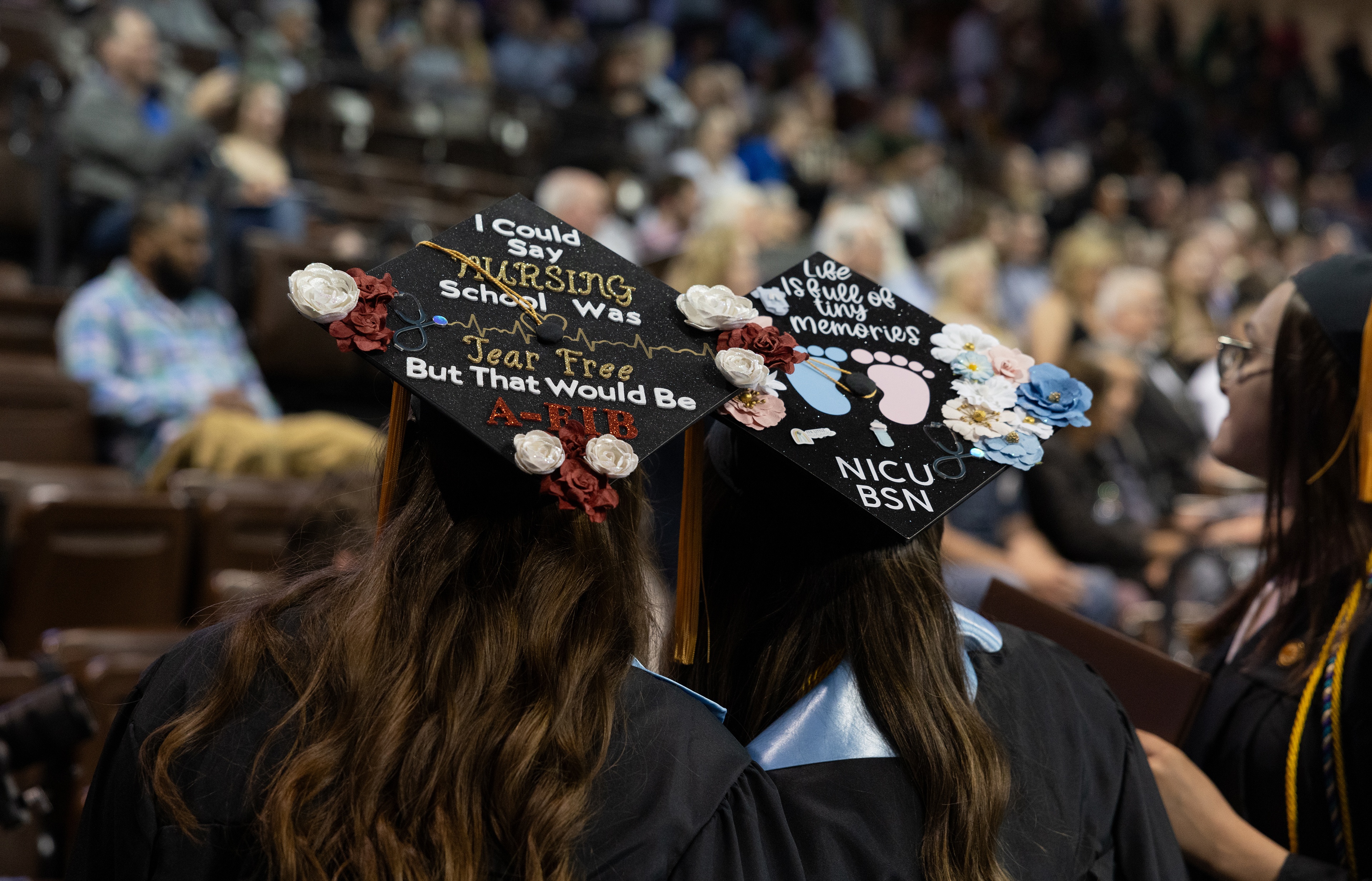 Two graduation caps are decorated with nursing profession motifs