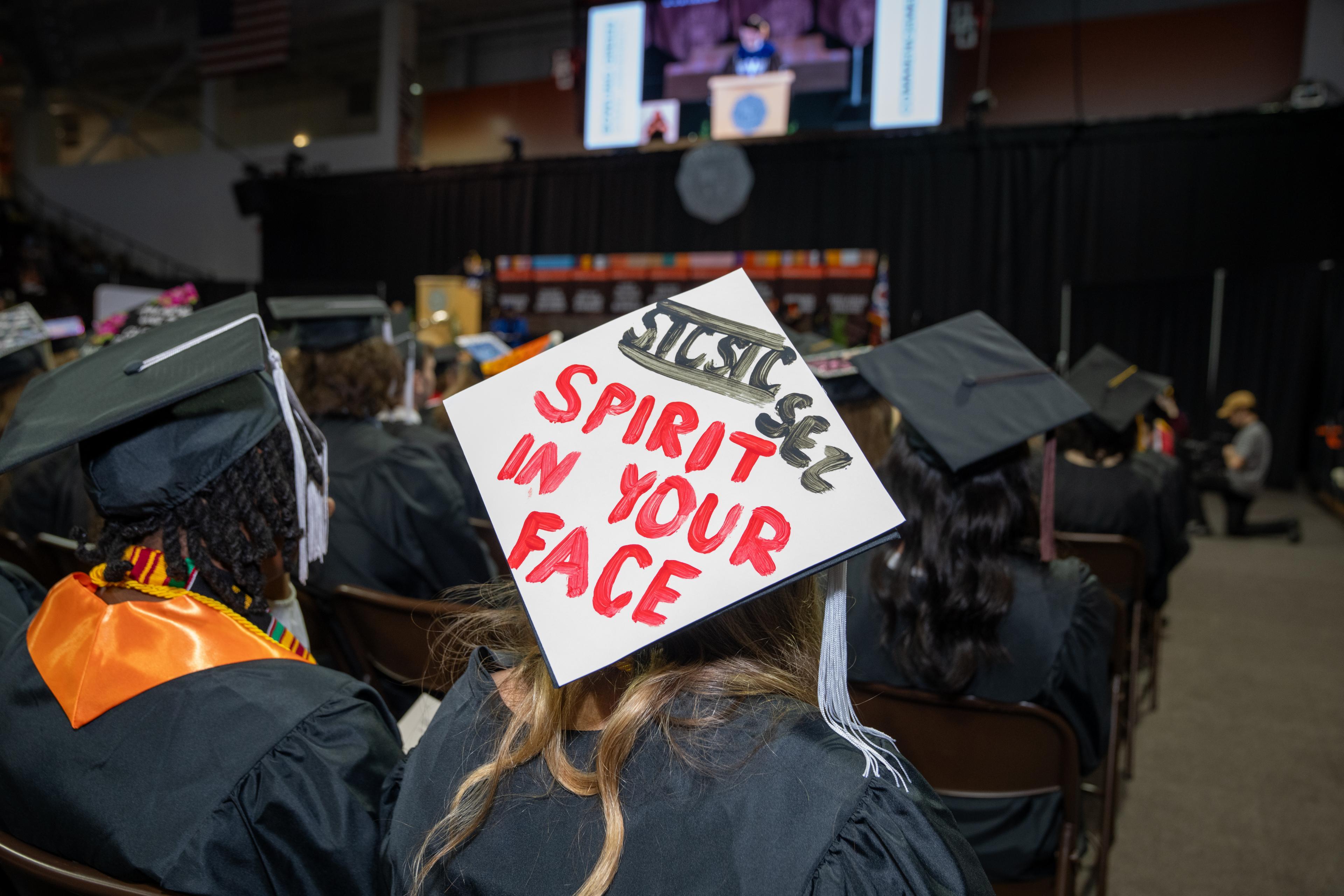 Gradution cap says, "SICSIC Sez Spirit in Your Face"