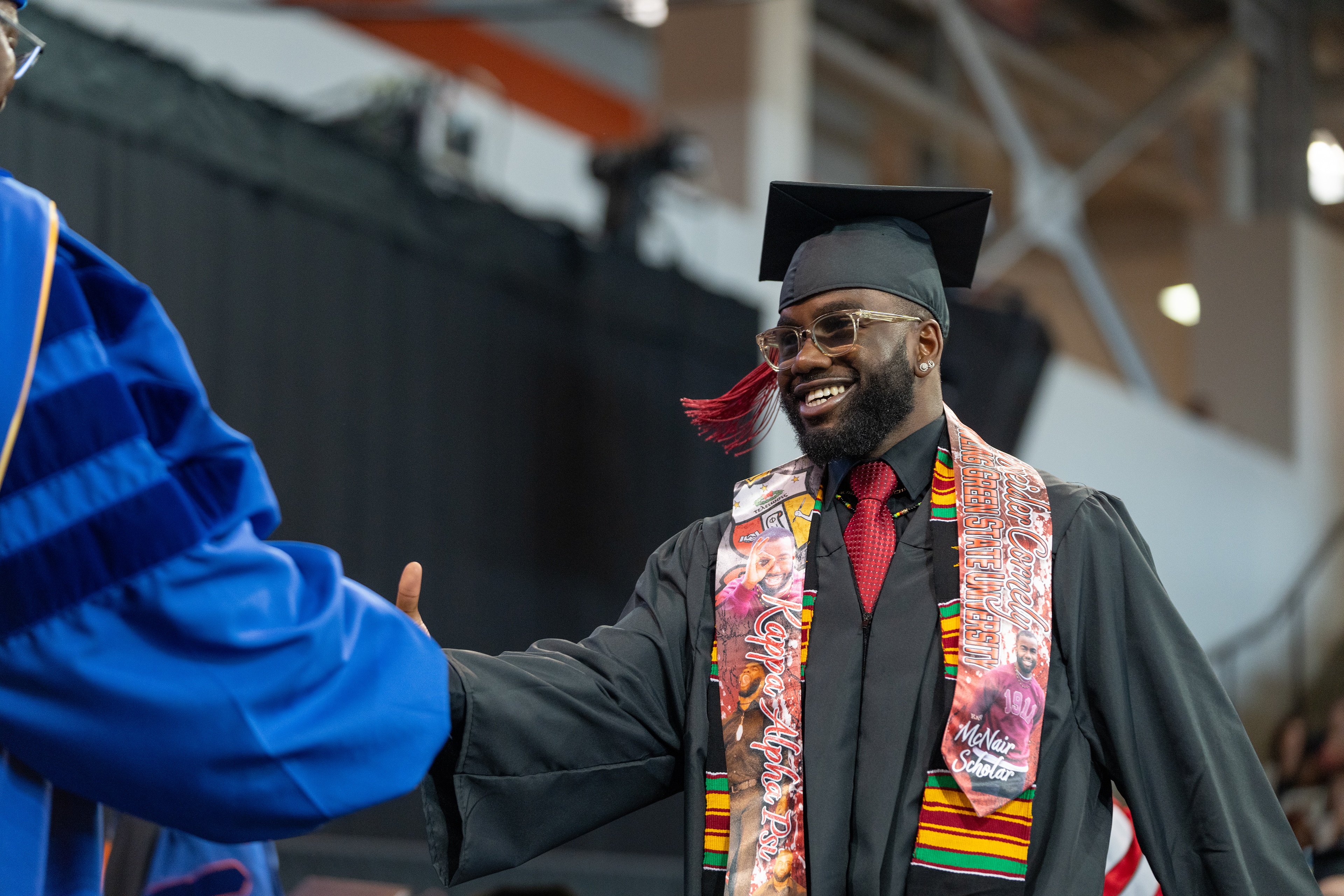 Young male graduate shakes hands with the provost
