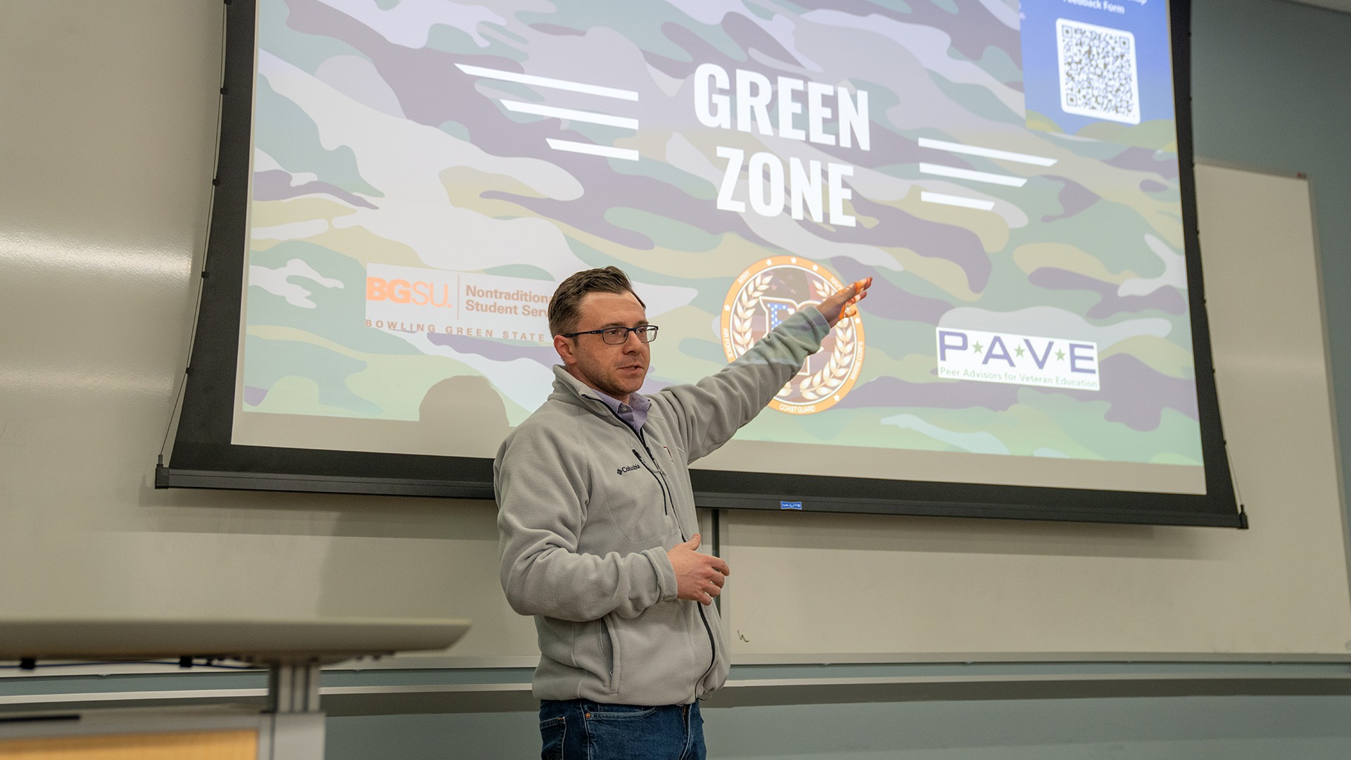 A person stands in front of a presentation screen with the words Green Zone.