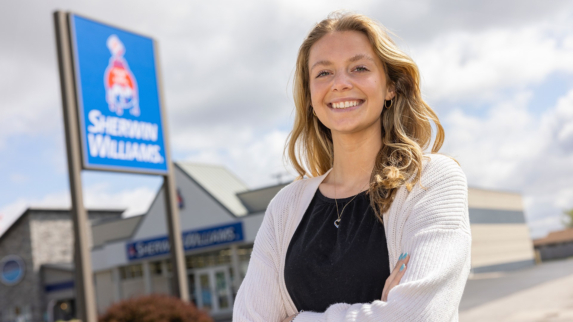 A person stands in front of a Sherwin-Williams sign.