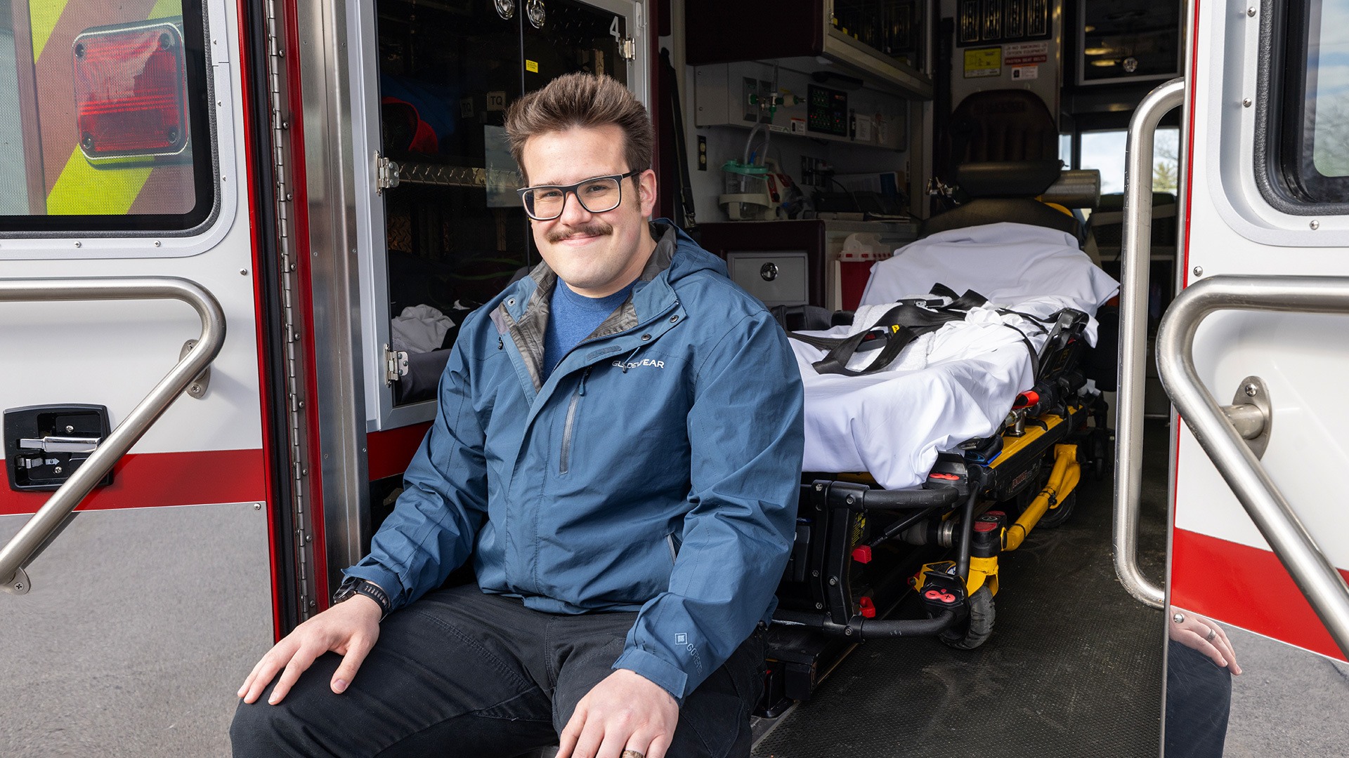 A person smiles while sitting in the back of an ambulance.