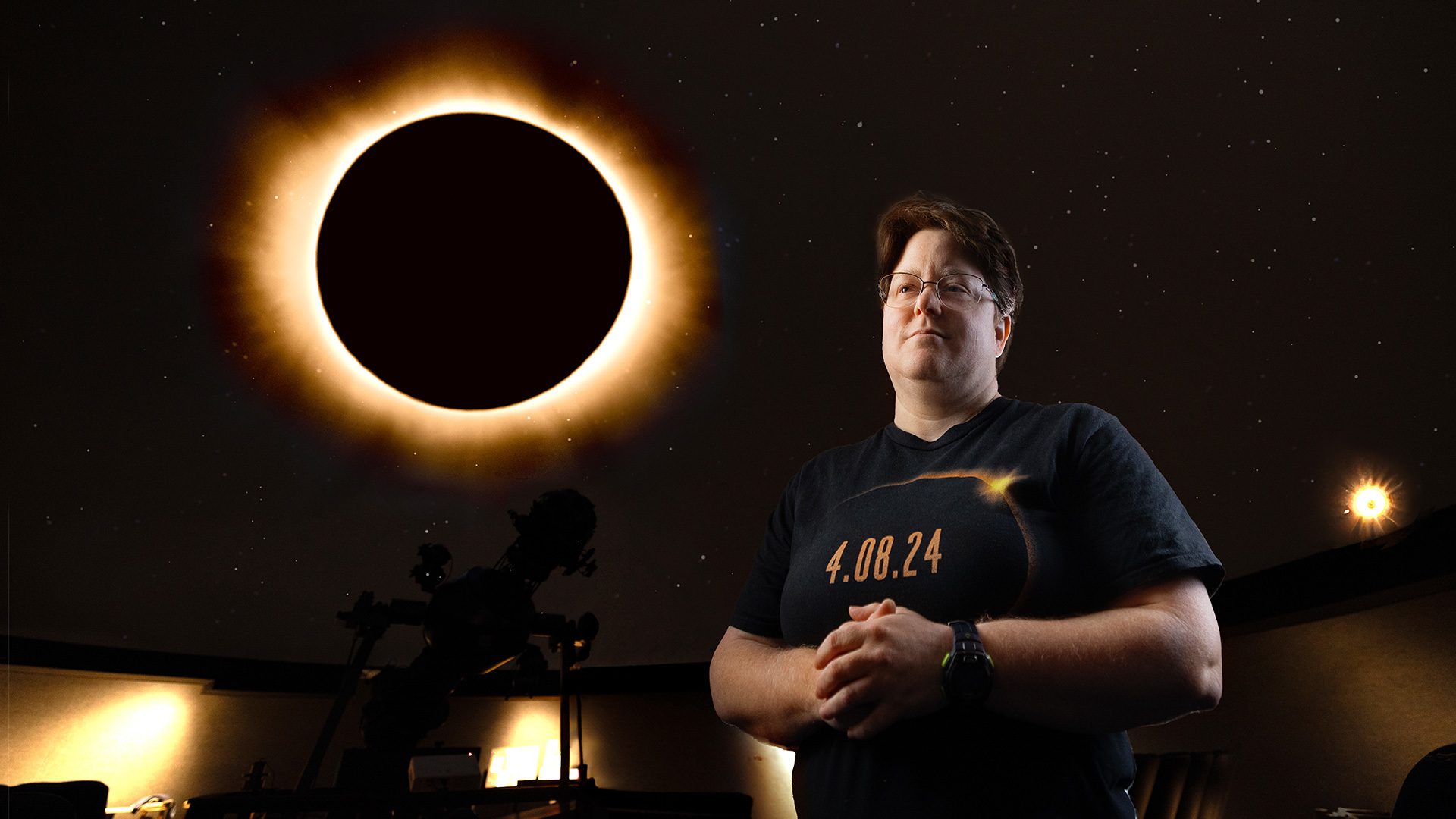 Kate Dellenbusch stands in front of an image of a solar eclipse.