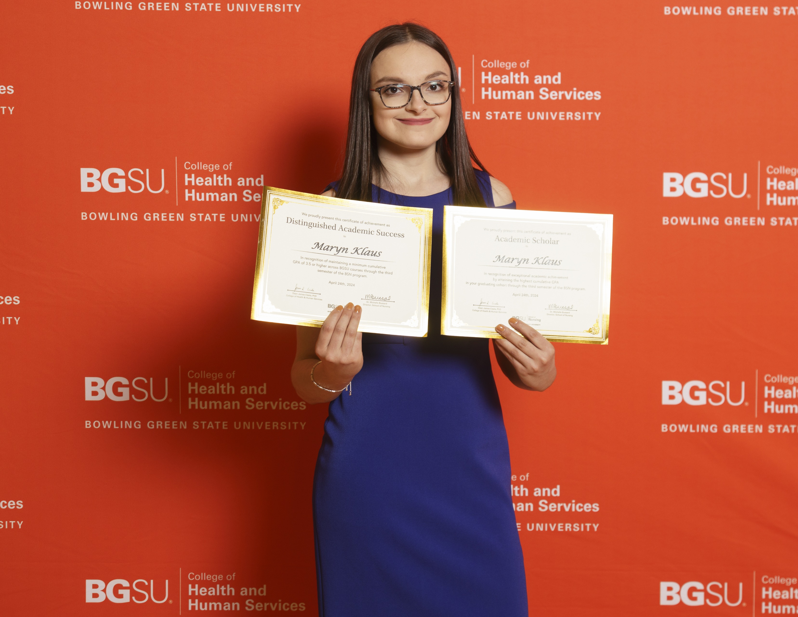 A person holds two awards certificates.