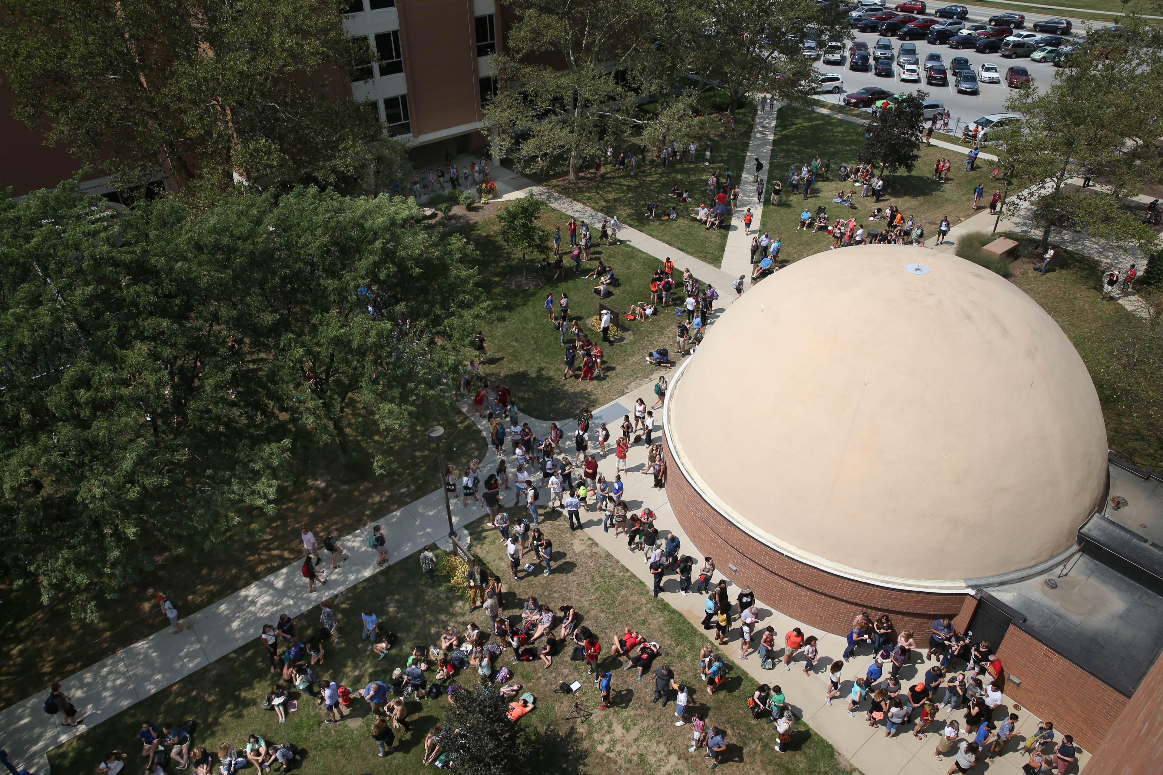 An aerial view of a planetarium with a large crowd gathered around it.