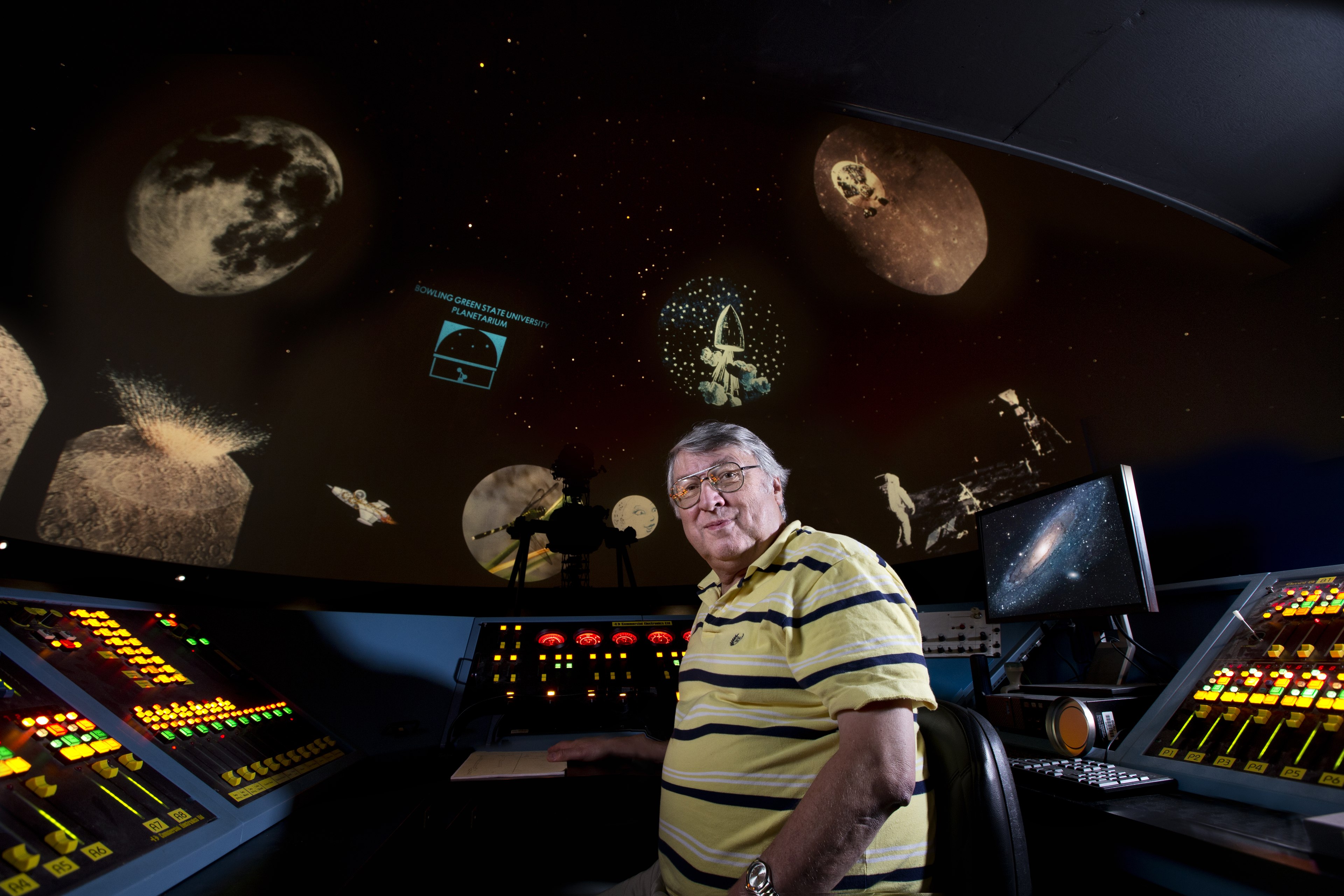 Dale Smith stands in front of a console with a solar system projection behind him.