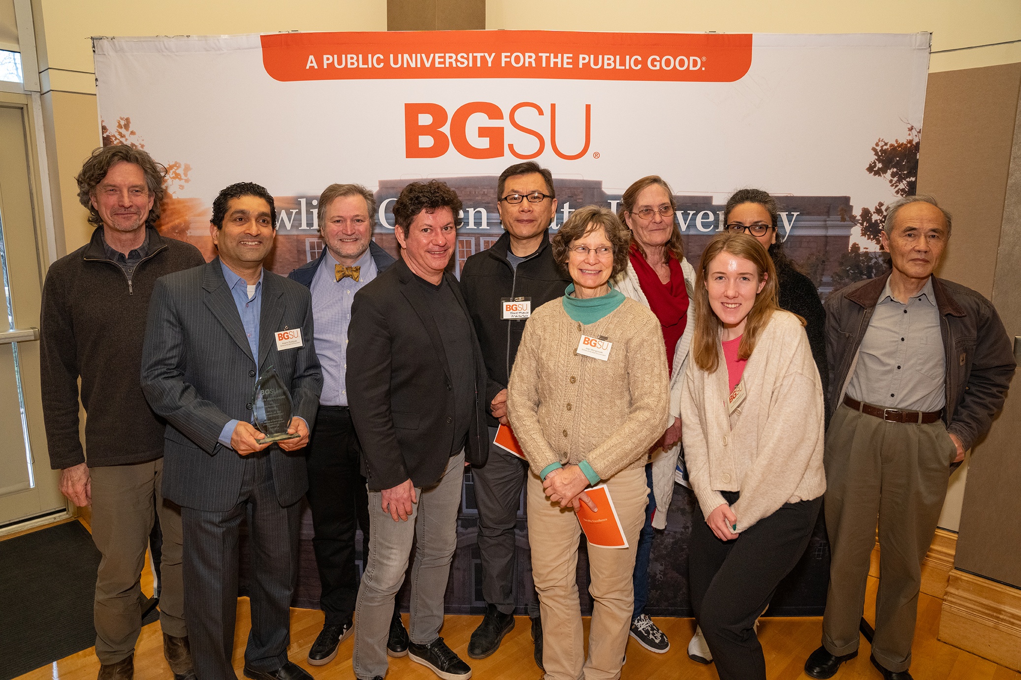 A group of people stand in front of a BGSU backdrop 