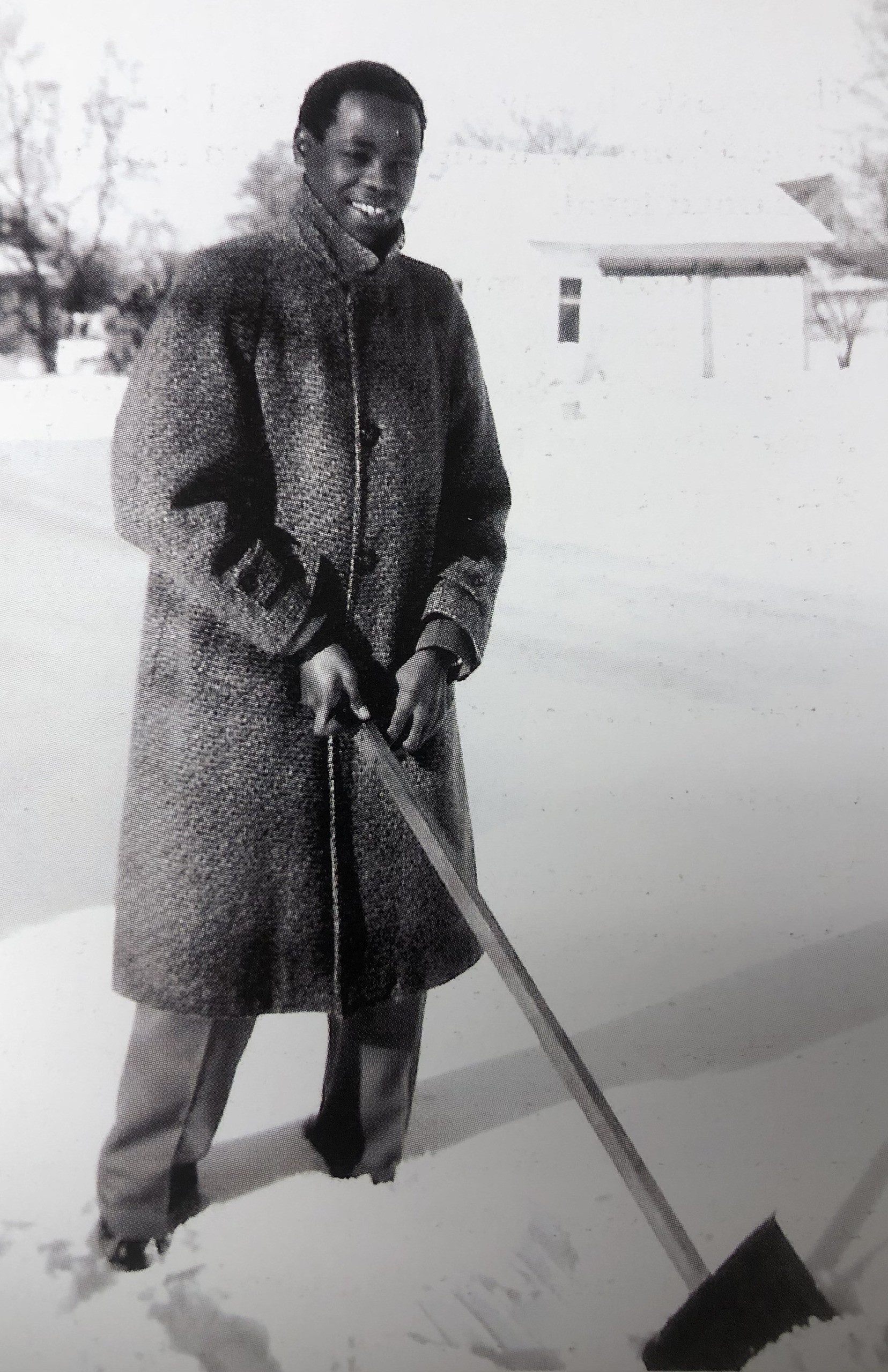 A man holds a snow shovel in a black and white photo.