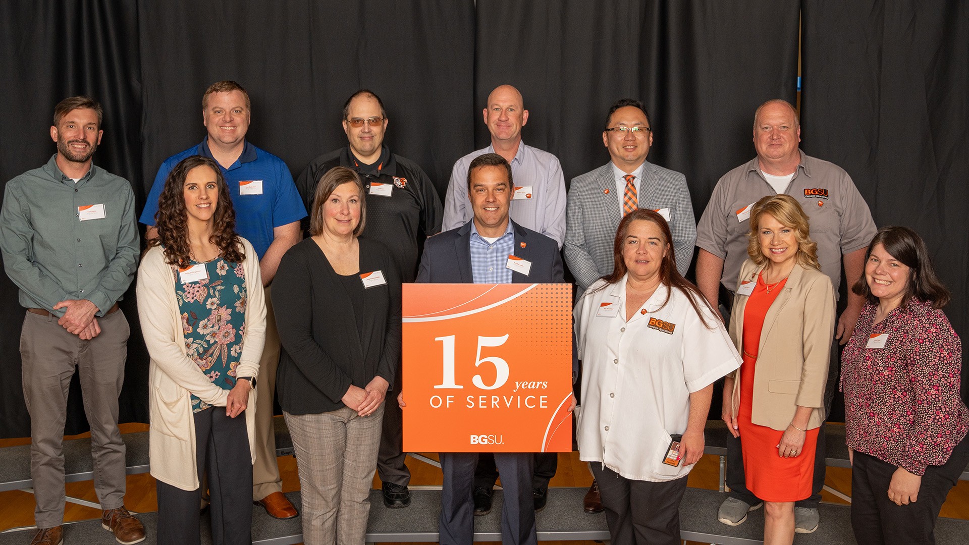 A group of people stand with a 15-year work anniversary sign